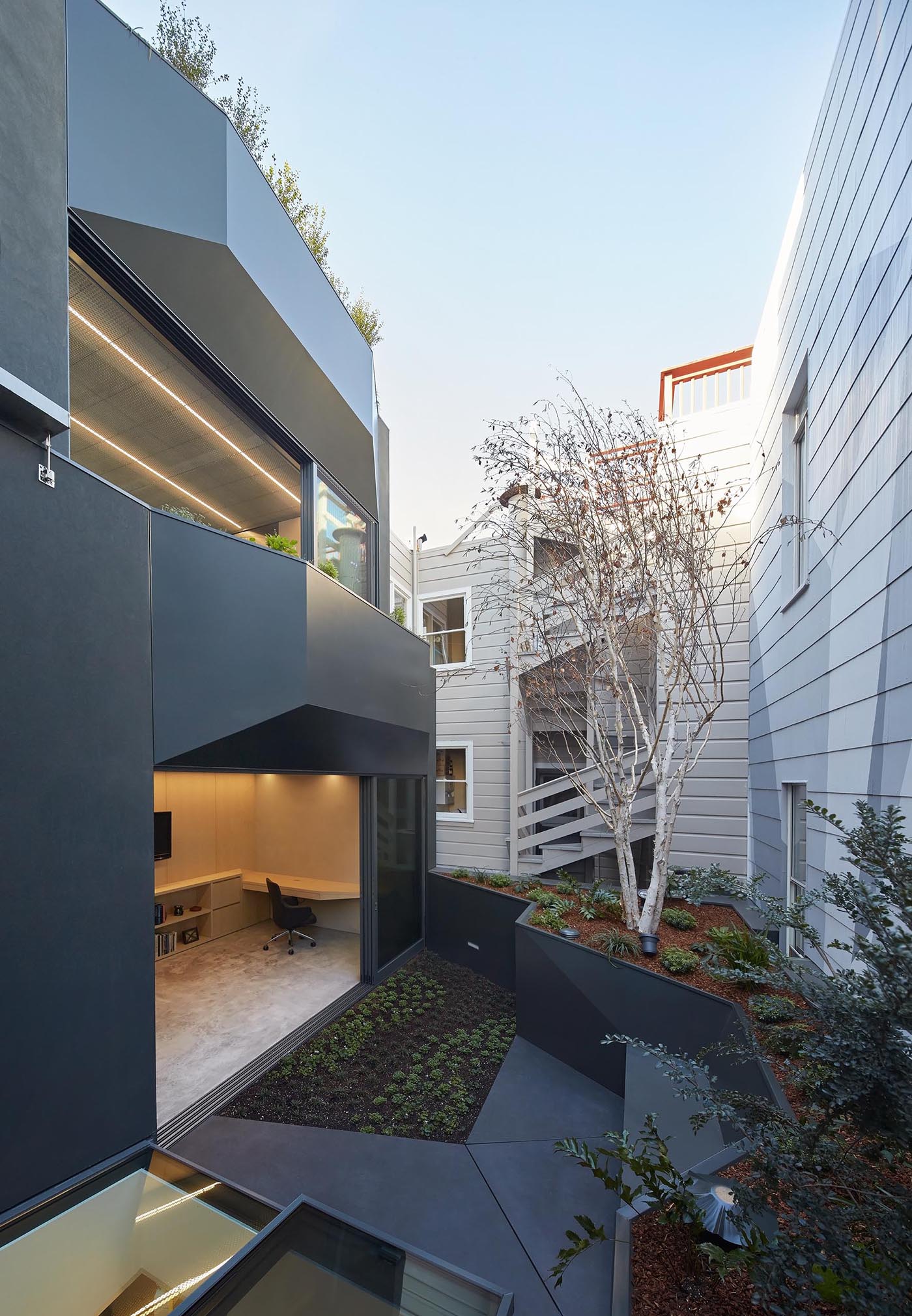 A modern home with a small rear garden that raised up creating room for a built-in bench.