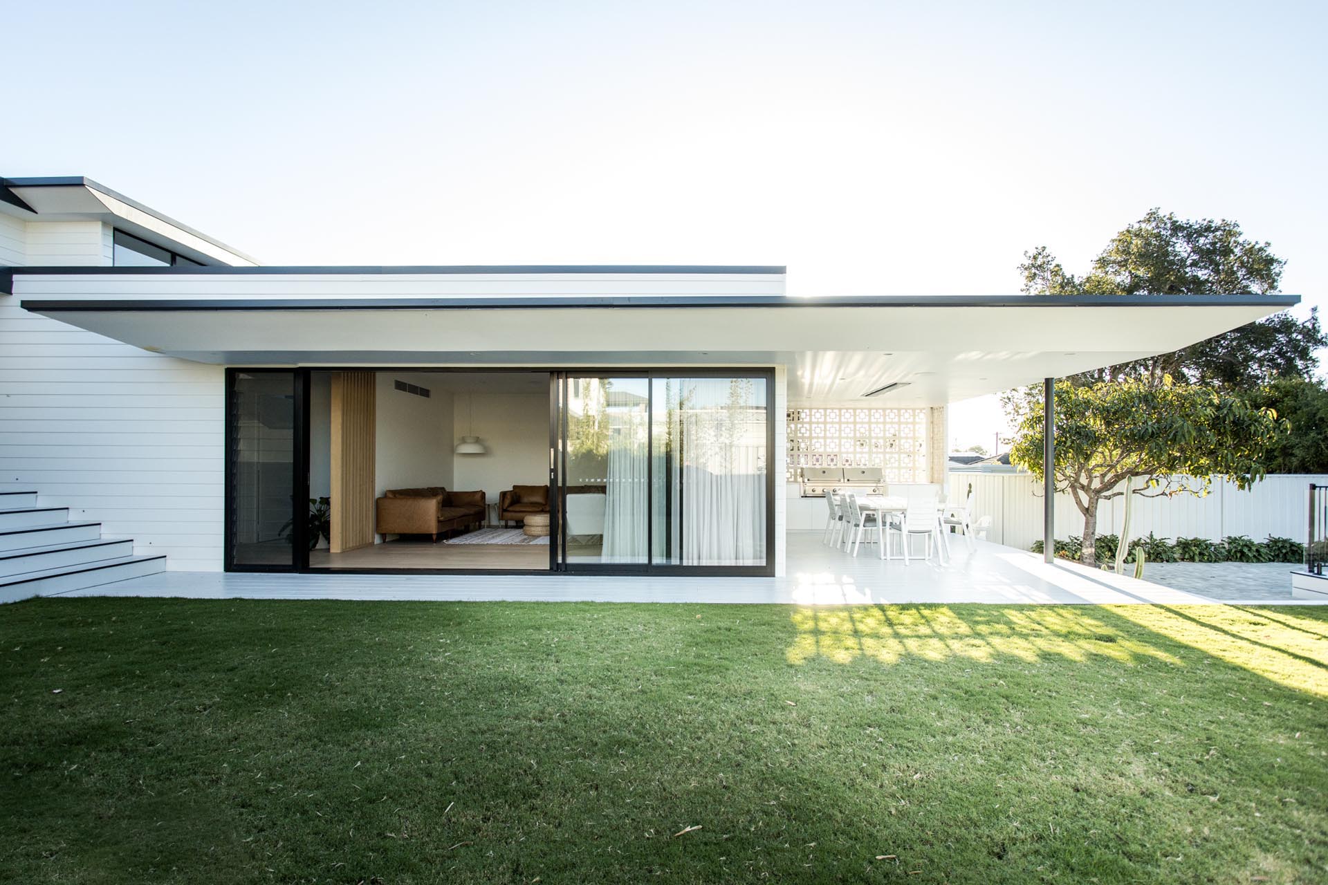 The rear of this modern home includes a covered outdoor kitchen and dining area, as well as a pool and expansive yard, where the home owners can relax and give the children space to roam.