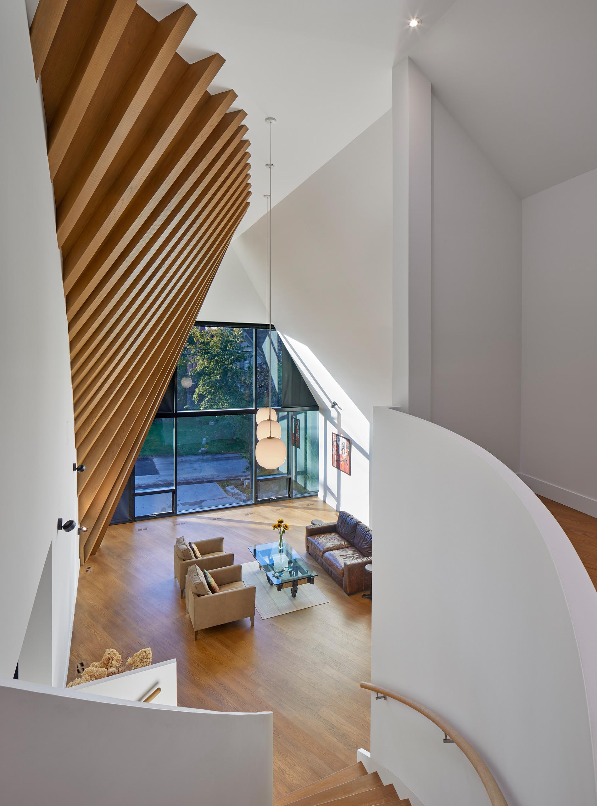 A modern home interior with exposed rafters clad with red oak veneer continue the roof’s dynamic shape. 