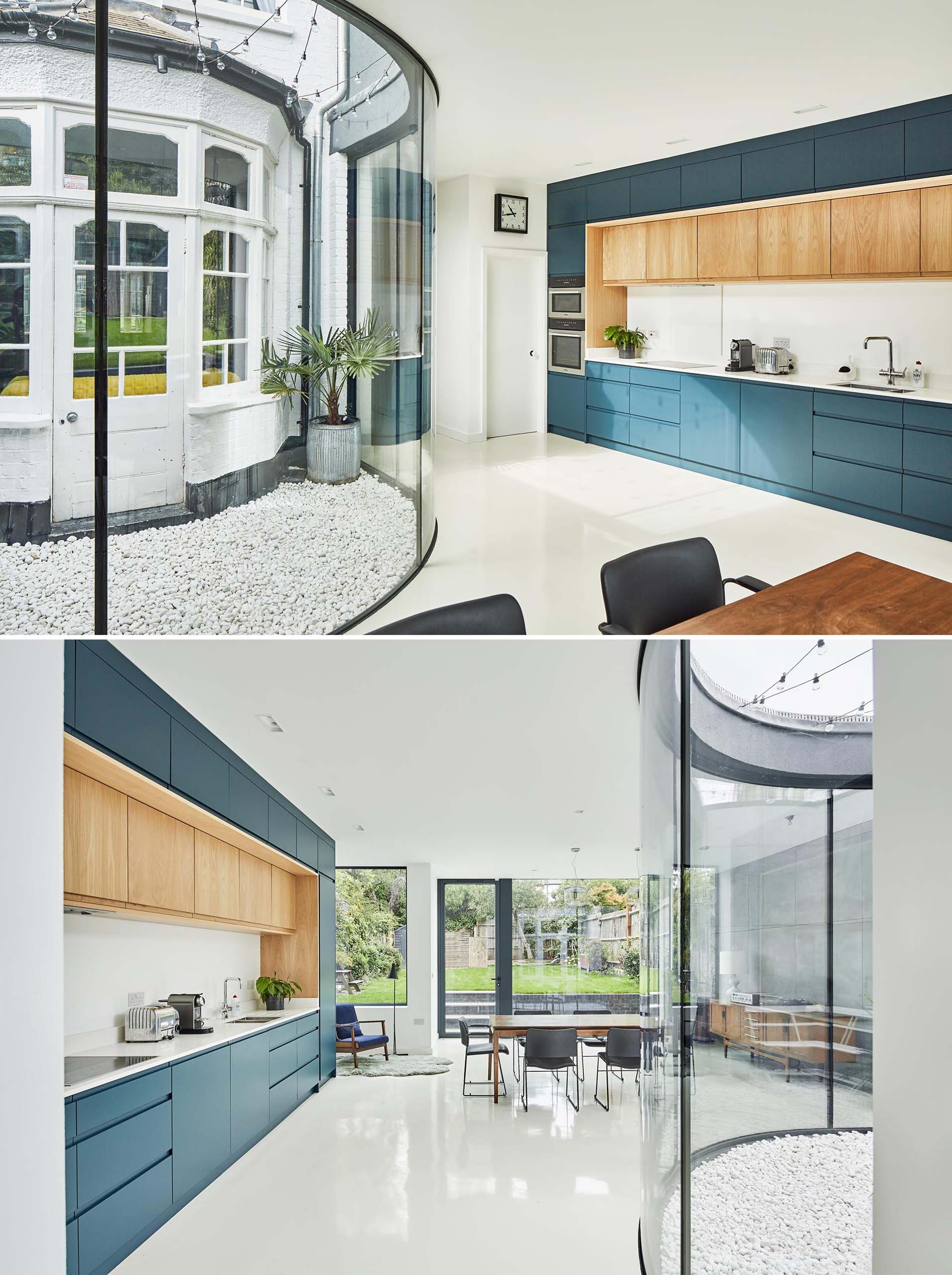A modern rear extension with a new open plan dining room and kitchen, with the dark blue kitchen cabinets adding a colorful accent to the space. A curved window provides views of a small courtyard and original bay window.