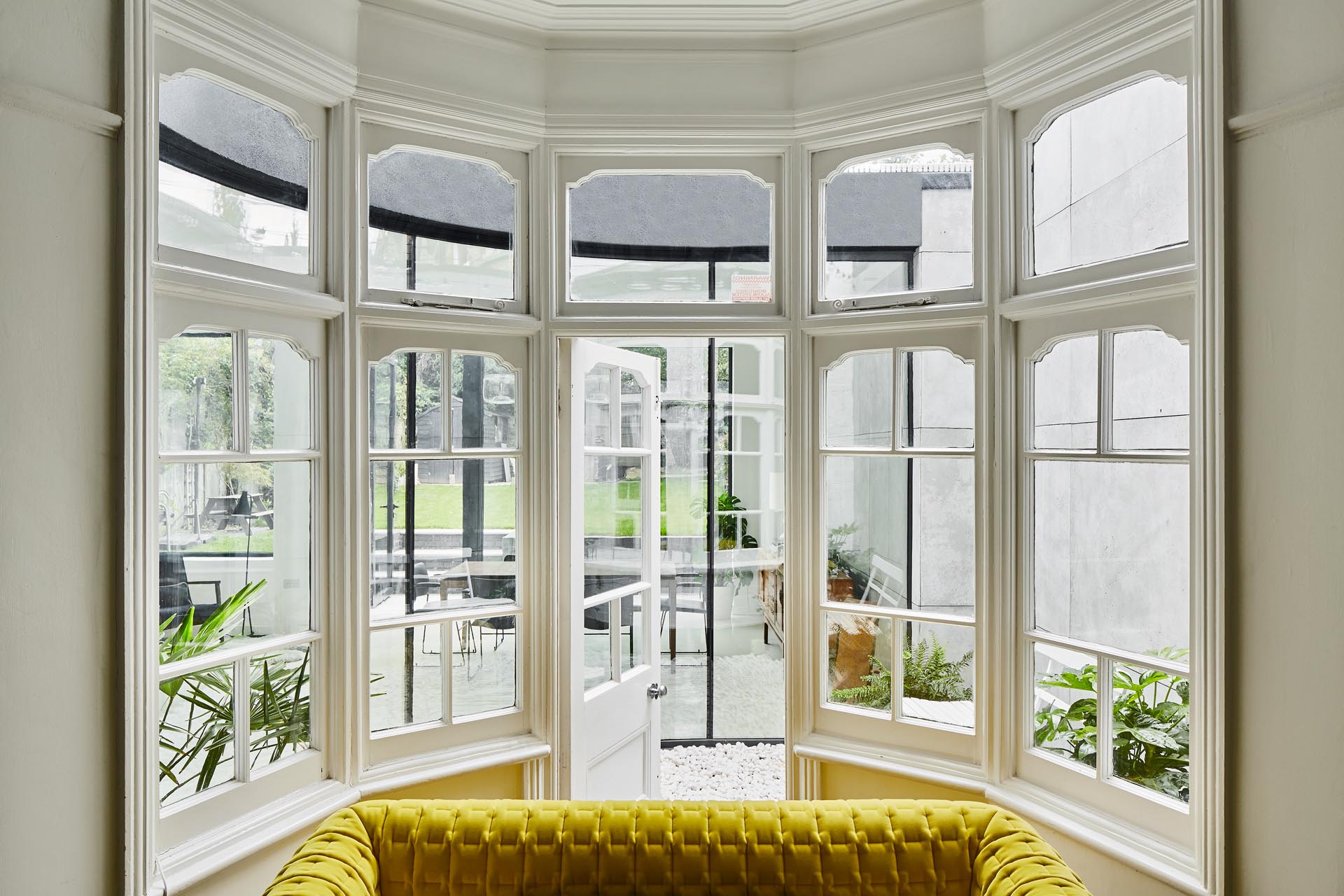 A bay window with a door opens to a small courtyard that has views of the new extension.