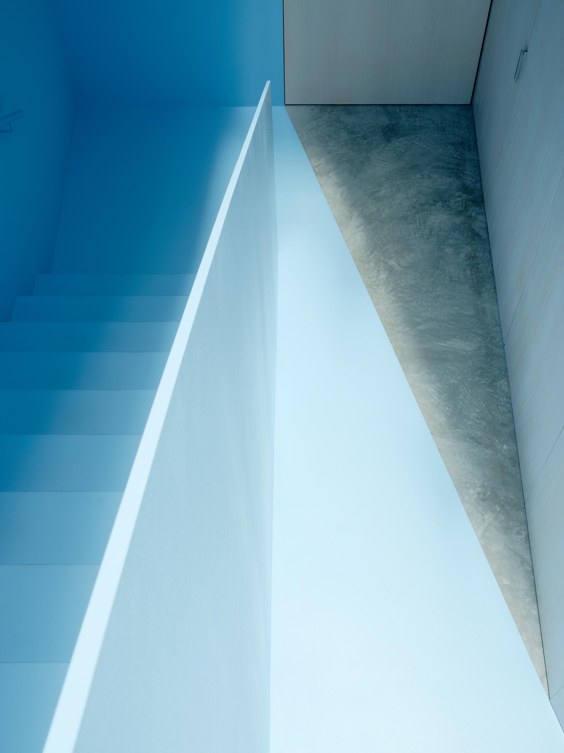 A modern home with a pastel blue staircase and painted floor.