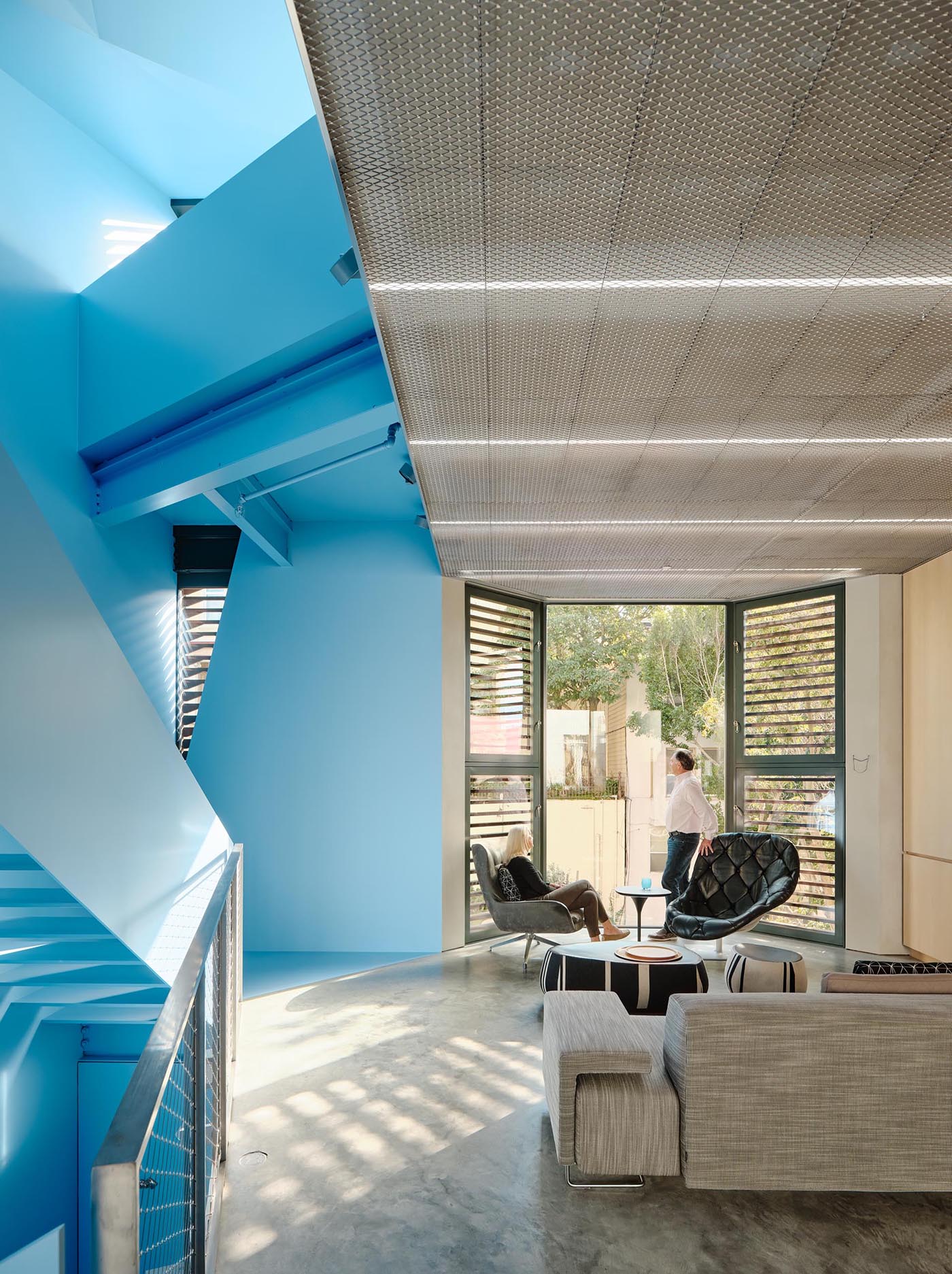 A modern home with a pastel blue staircase, and a living room with a high ceiling and bay window.