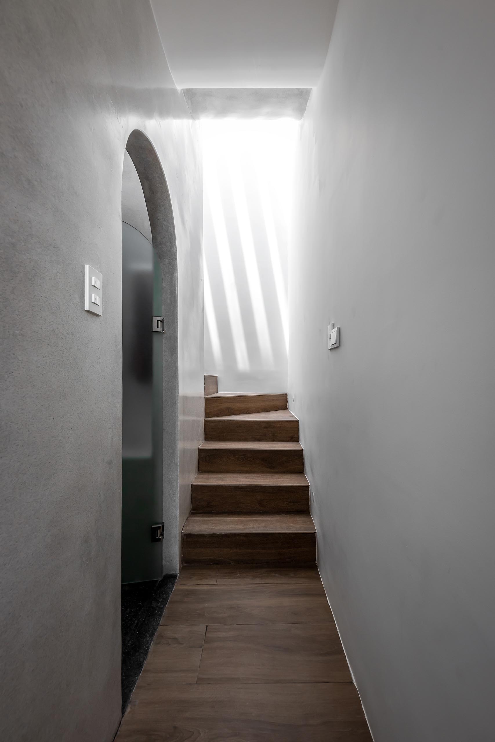 A modern home with stairs that are lit by skylights and spotlights.