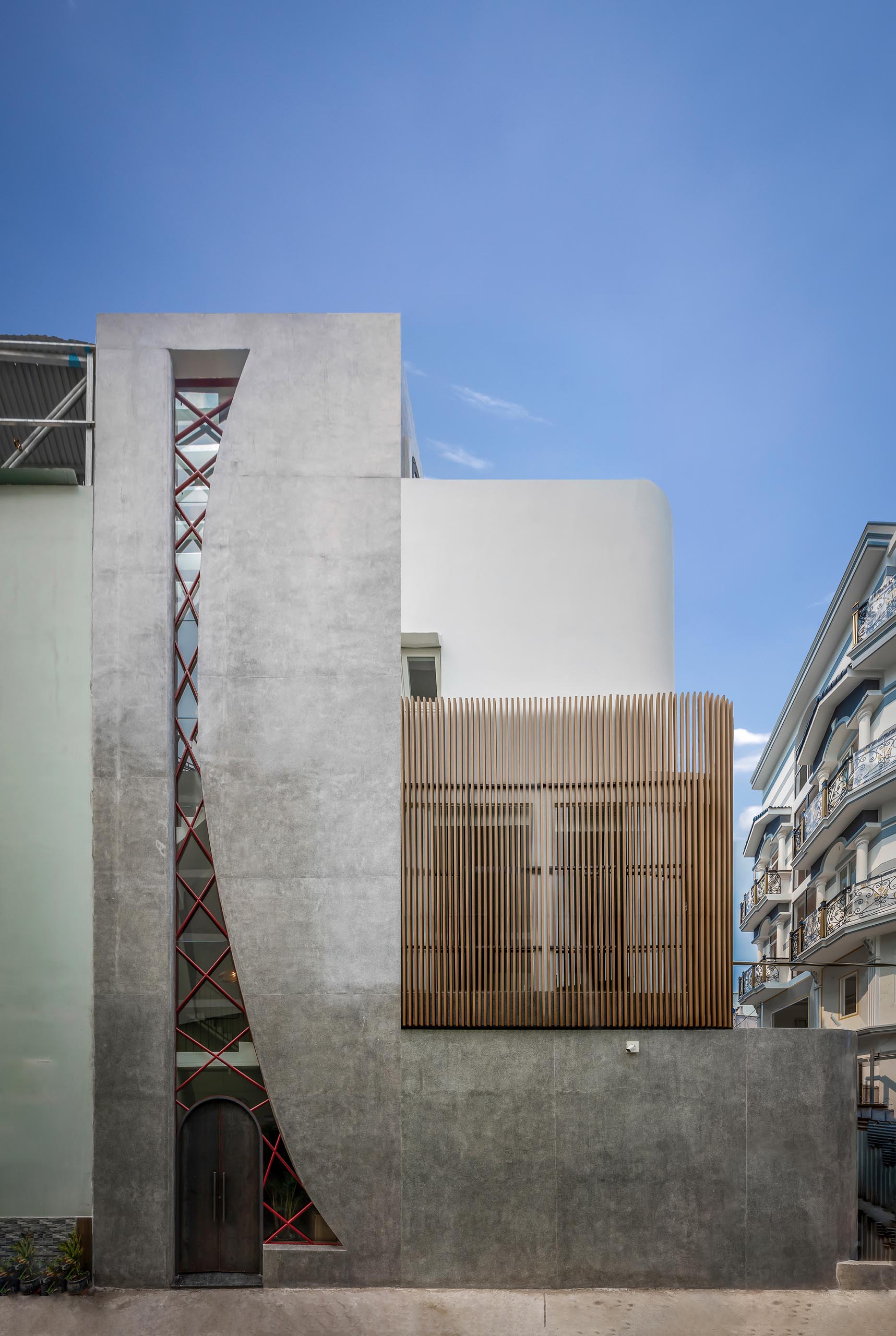 A modern concrete house with an irregular shaped window, also incorporates the steel arched front door.