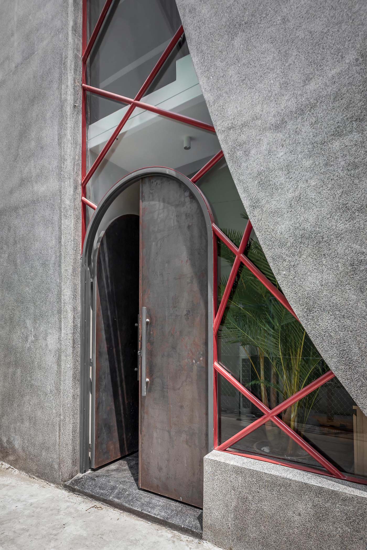 The large arched front door is made from steel, giving it an industrial look when paired with the concrete exterior.