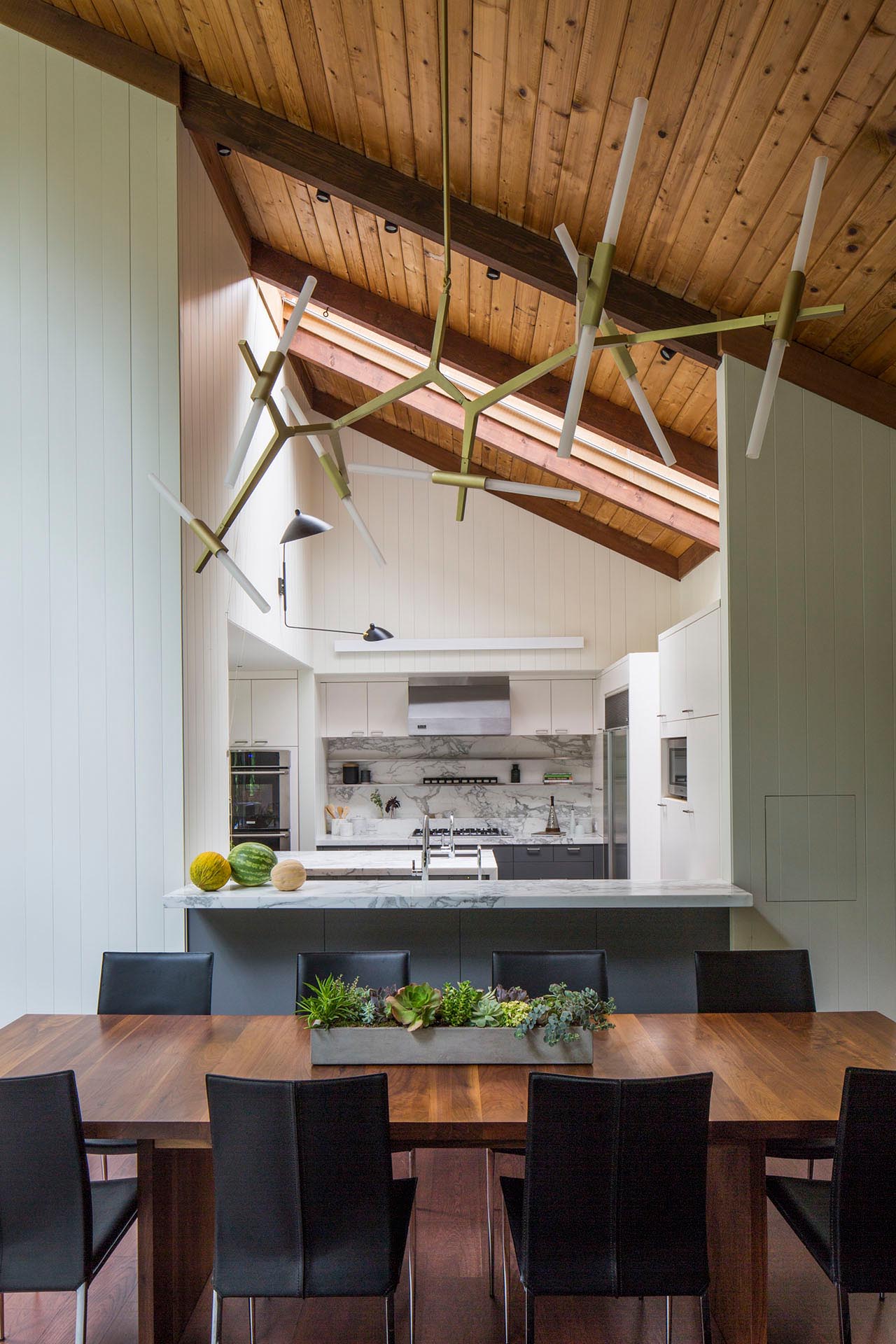 A modern kitchen which includes minimalist white and gray cabinets, a breakfast bar, and an island with a waterfall countertop.