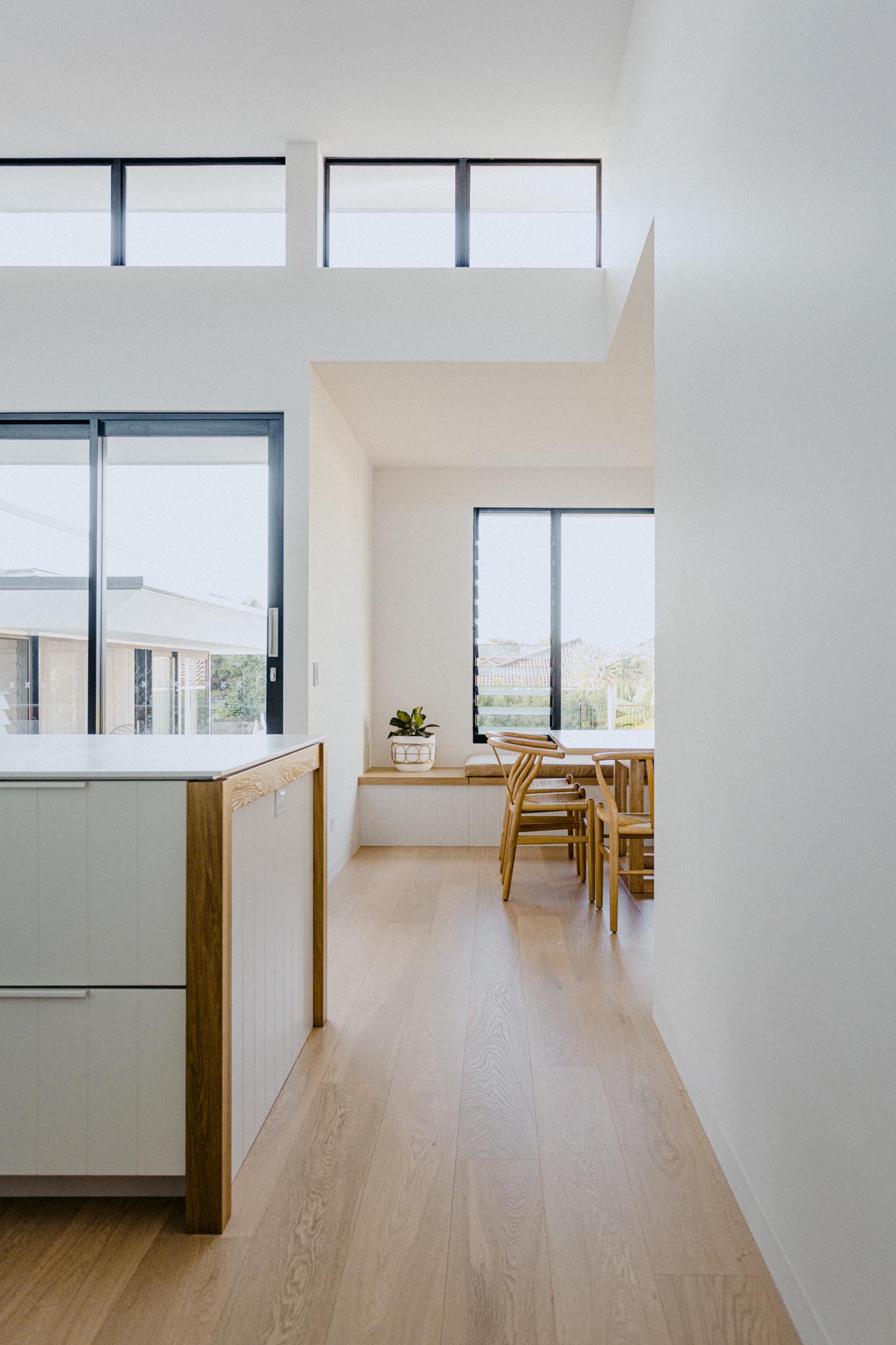 A modern home interior with floor flooring, large windows, a dining area with built-in kitchen, and minimalist kitchen.