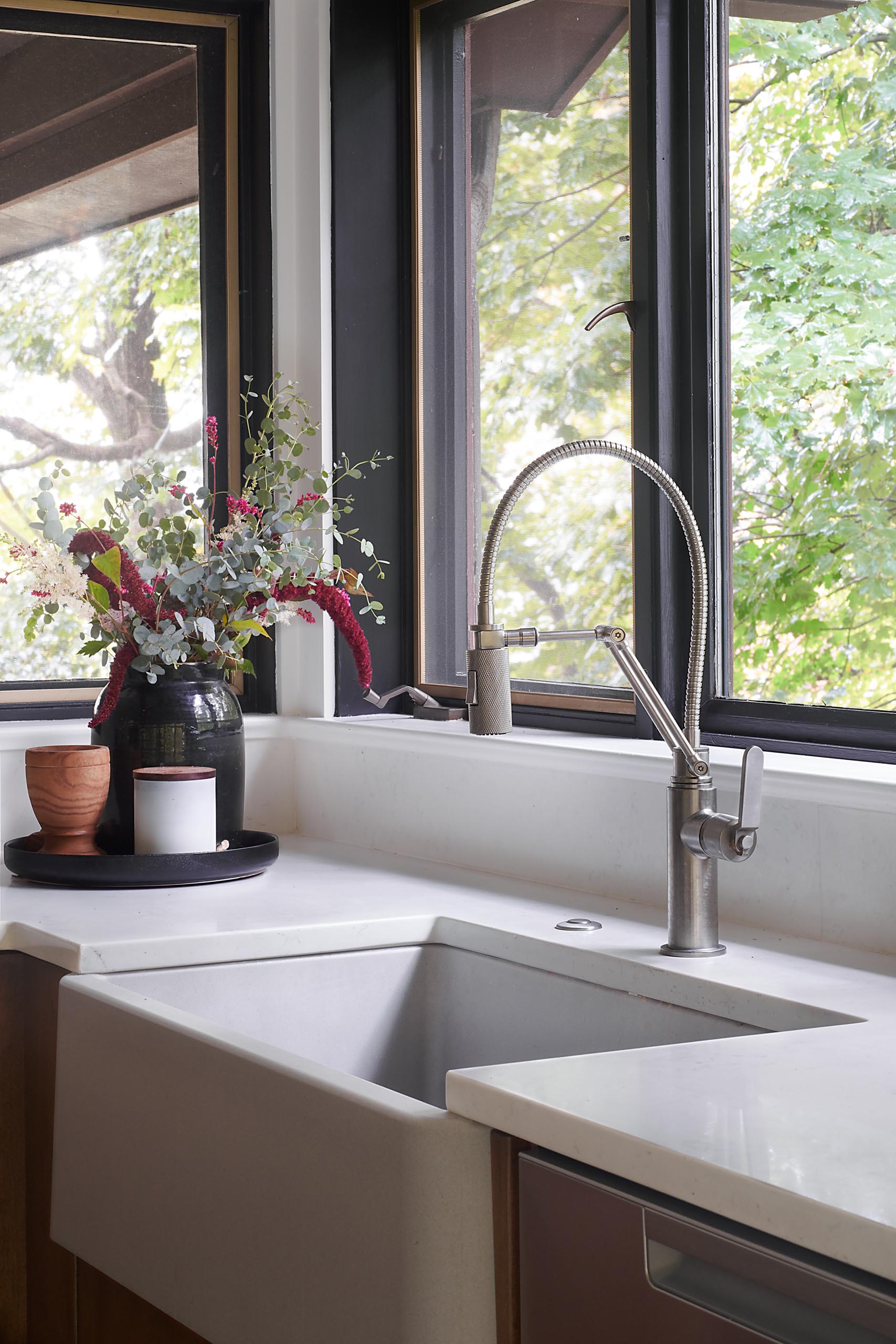 A modern kitchen with white countertops and an apron sink.