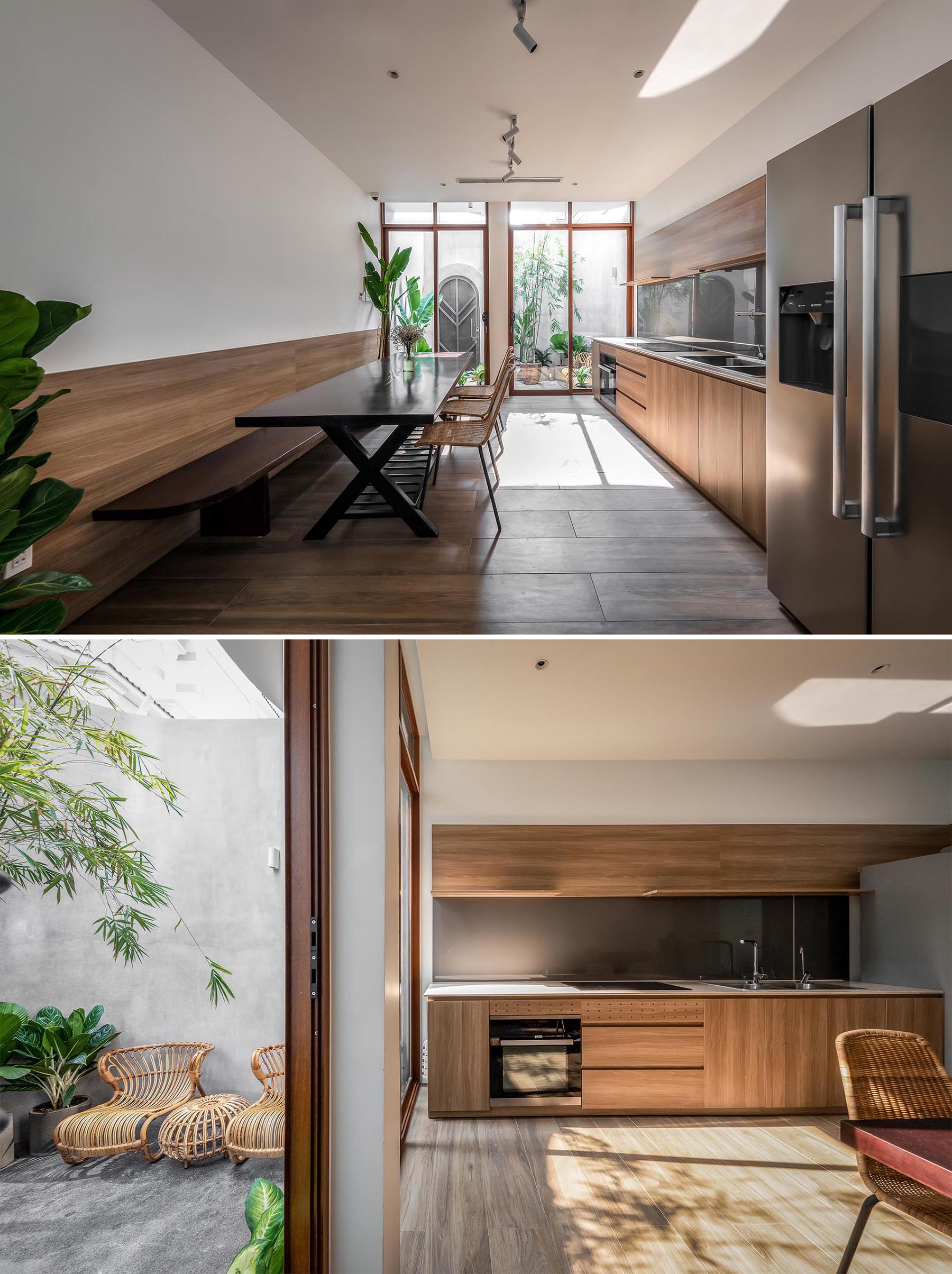 An open plan dining room and kitchen, where wood elements, like the dining bench and kitchen cabinets, complement the natural greenery of the indoor plants.