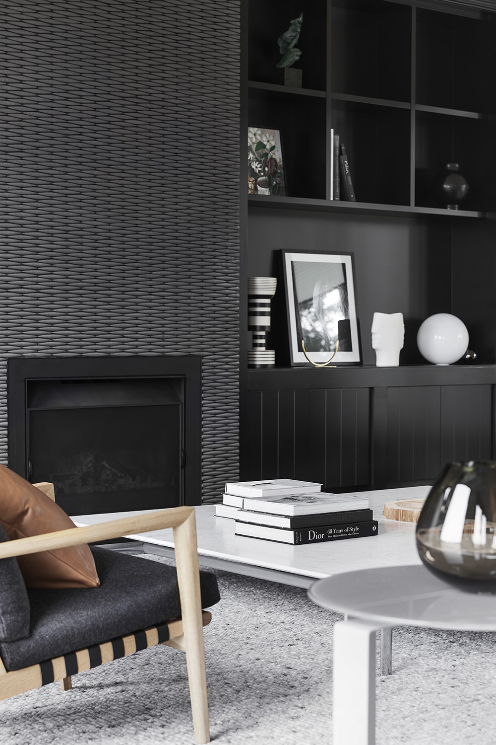 Modern black shelving and cabinetry can be found on either side of a focal fireplace with a silvery-grey tiled surround.