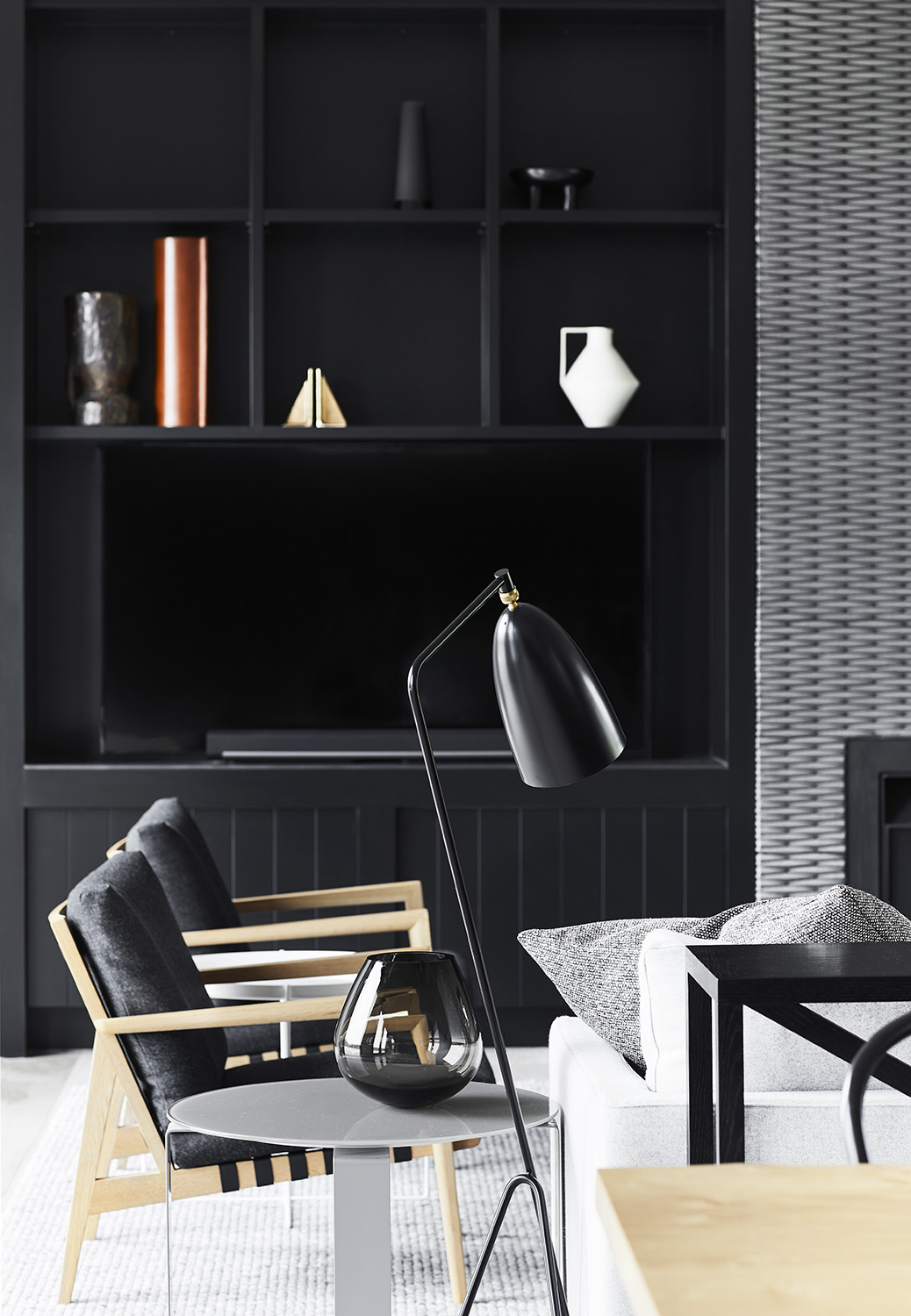 Modern black shelving and cabinetry can be found on either side of a focal fireplace with a silvery-grey tiled surround.