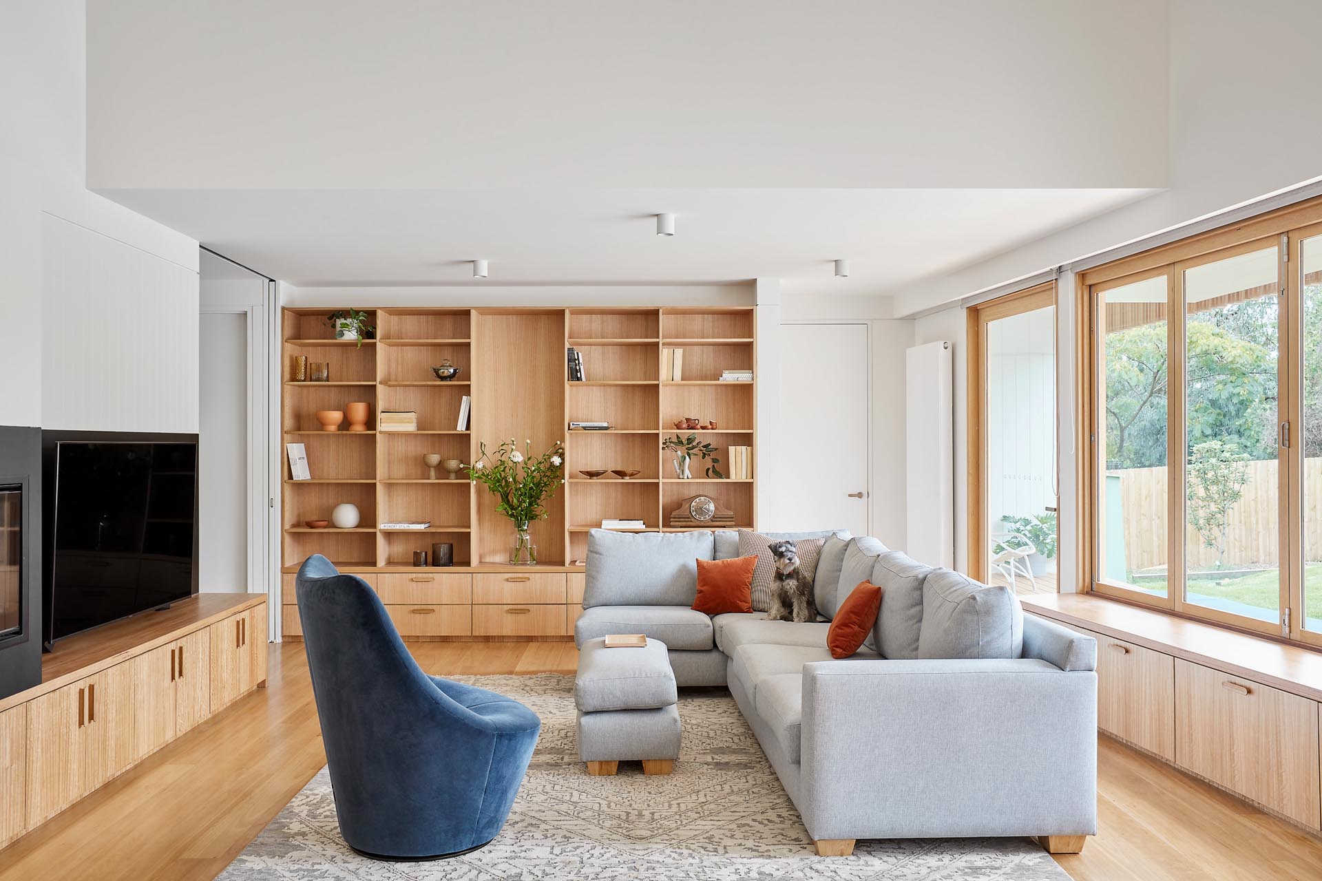 A modern living room with a custom designed wood shelving unit that includes drawers underneath.