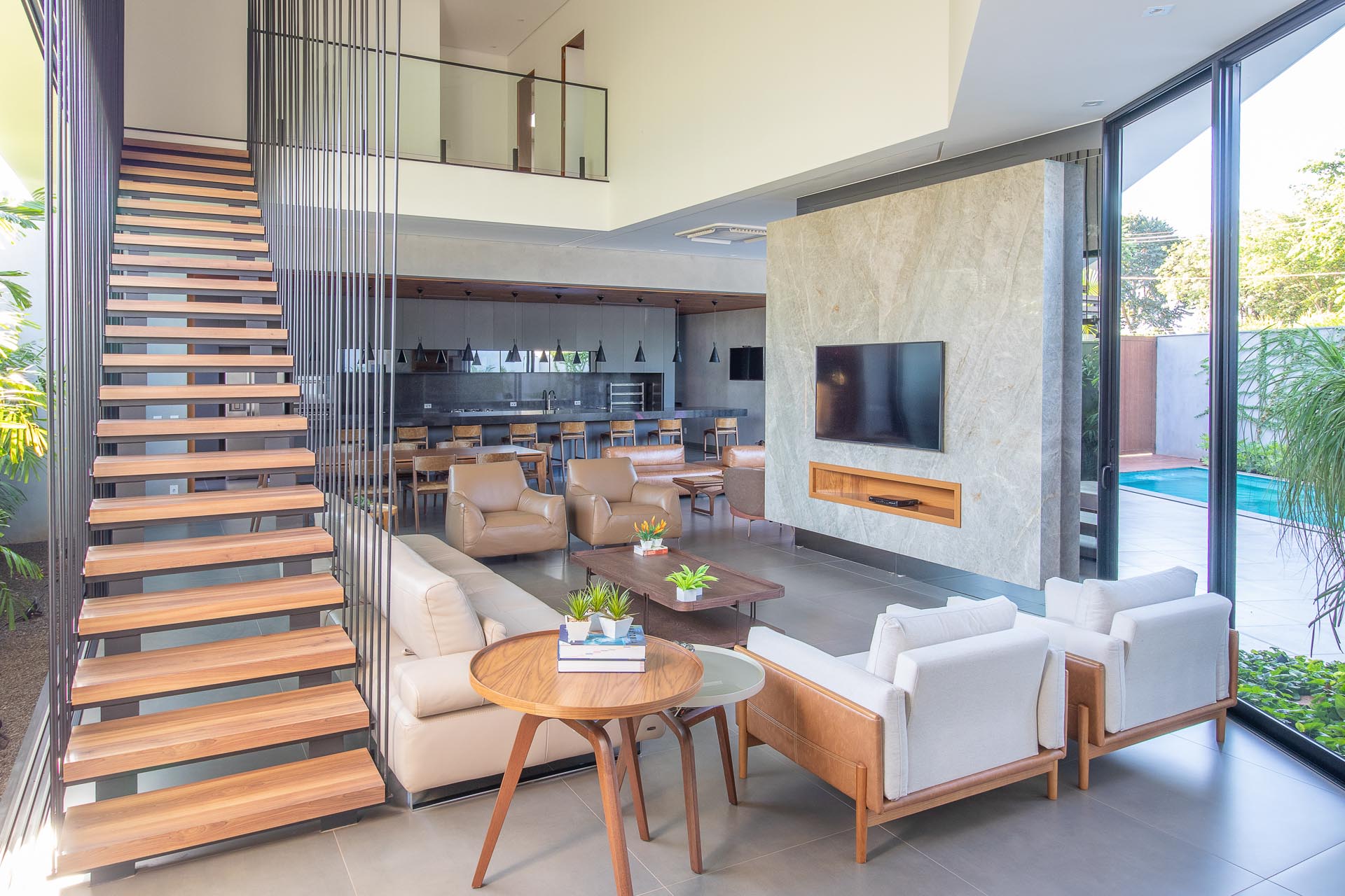 This mdoern living room is flooded with natural light from the oversized windows and sliding doors, while the stairs draw attention to the double height ceiling.