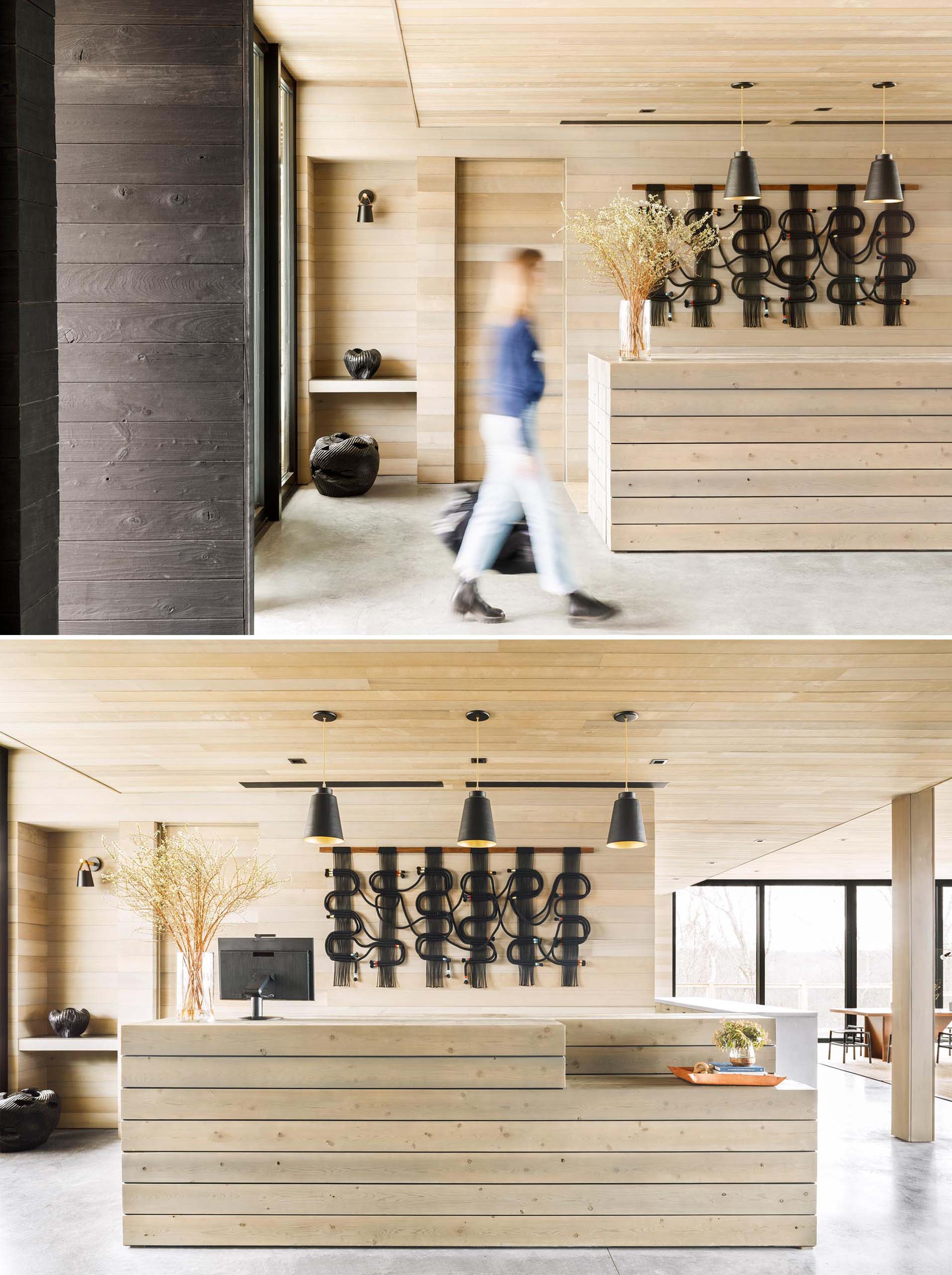 A modern lobby with a wood welcome desk that matches the wood walls and ceiling.