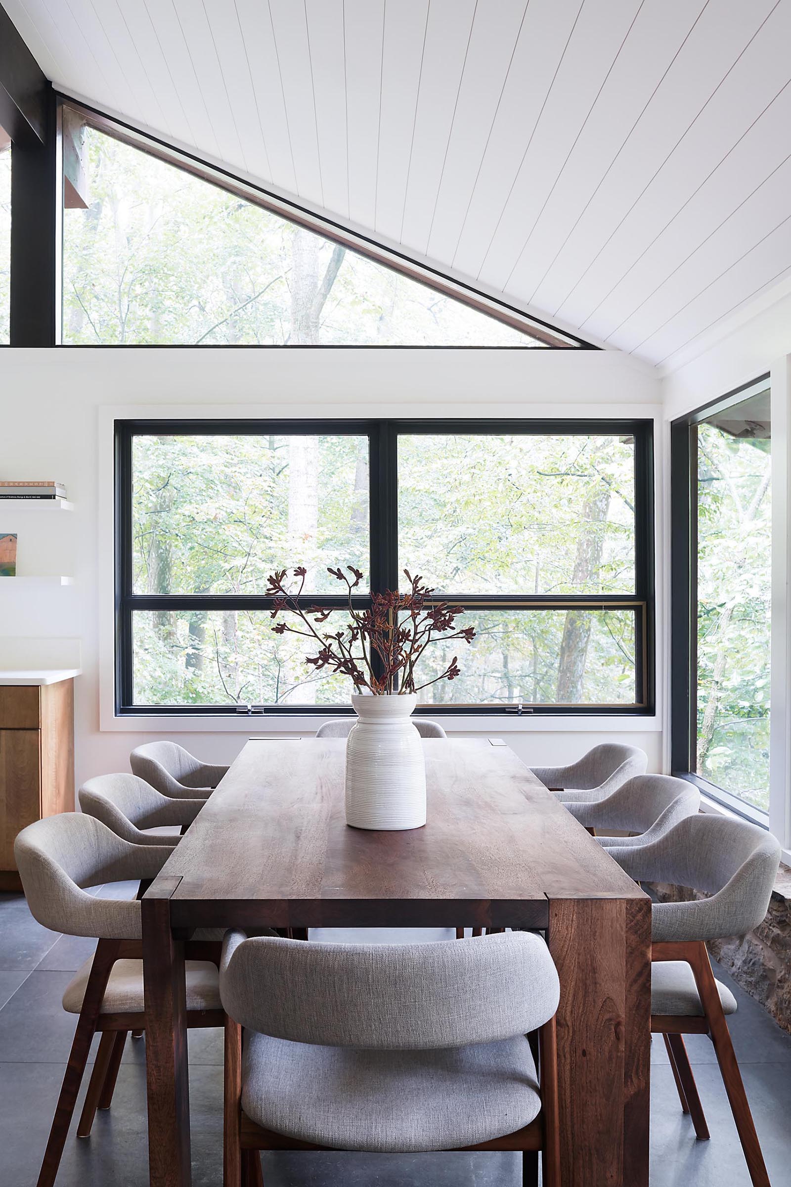 A modern dining room surrounded by windows has large format floor tiles.