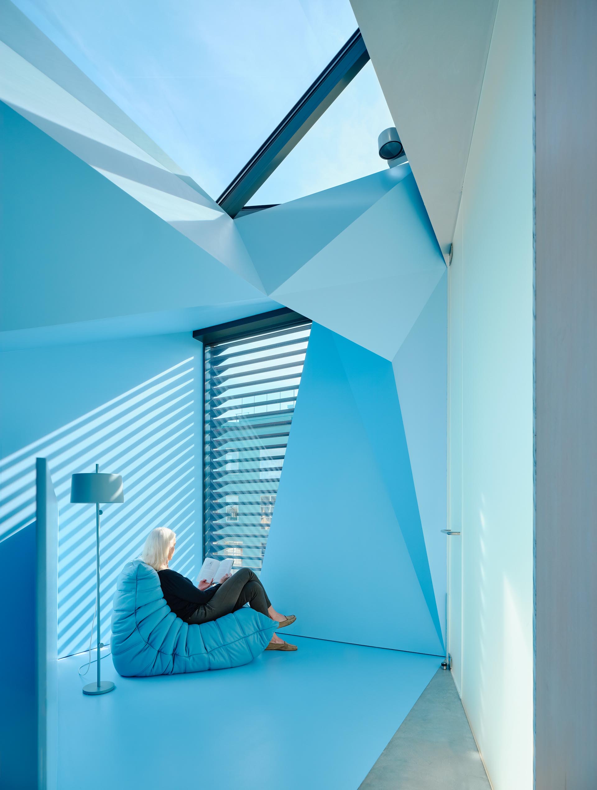 A skylight fills the top level of this modern home with natural light, while a small sitting area looks out the window onto the neighborhood.