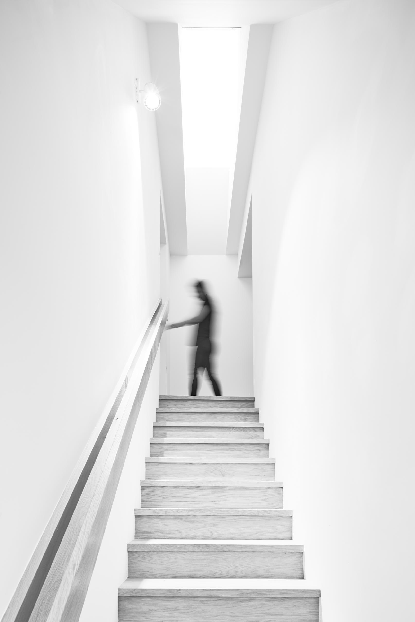 A staircase surrounded by white walls connects the social areas with the bedrooms and bathrooms on the upper floors of the home.