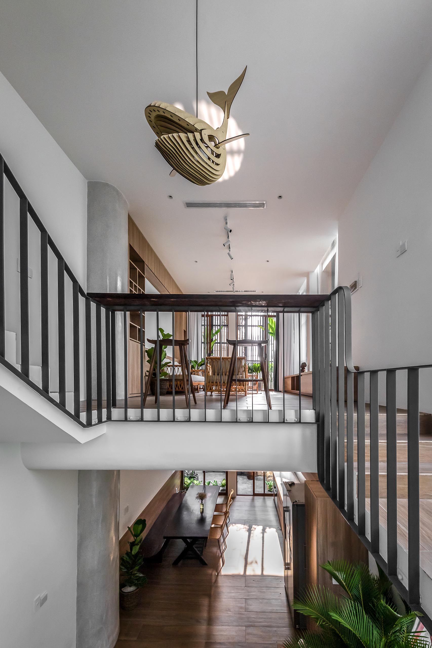 Before reaching the living room of this modern home, there's a small bar area built into the design of the black handrail. From this angle, you're able to see the wood wall sculpture light that hangs from the ceiling.