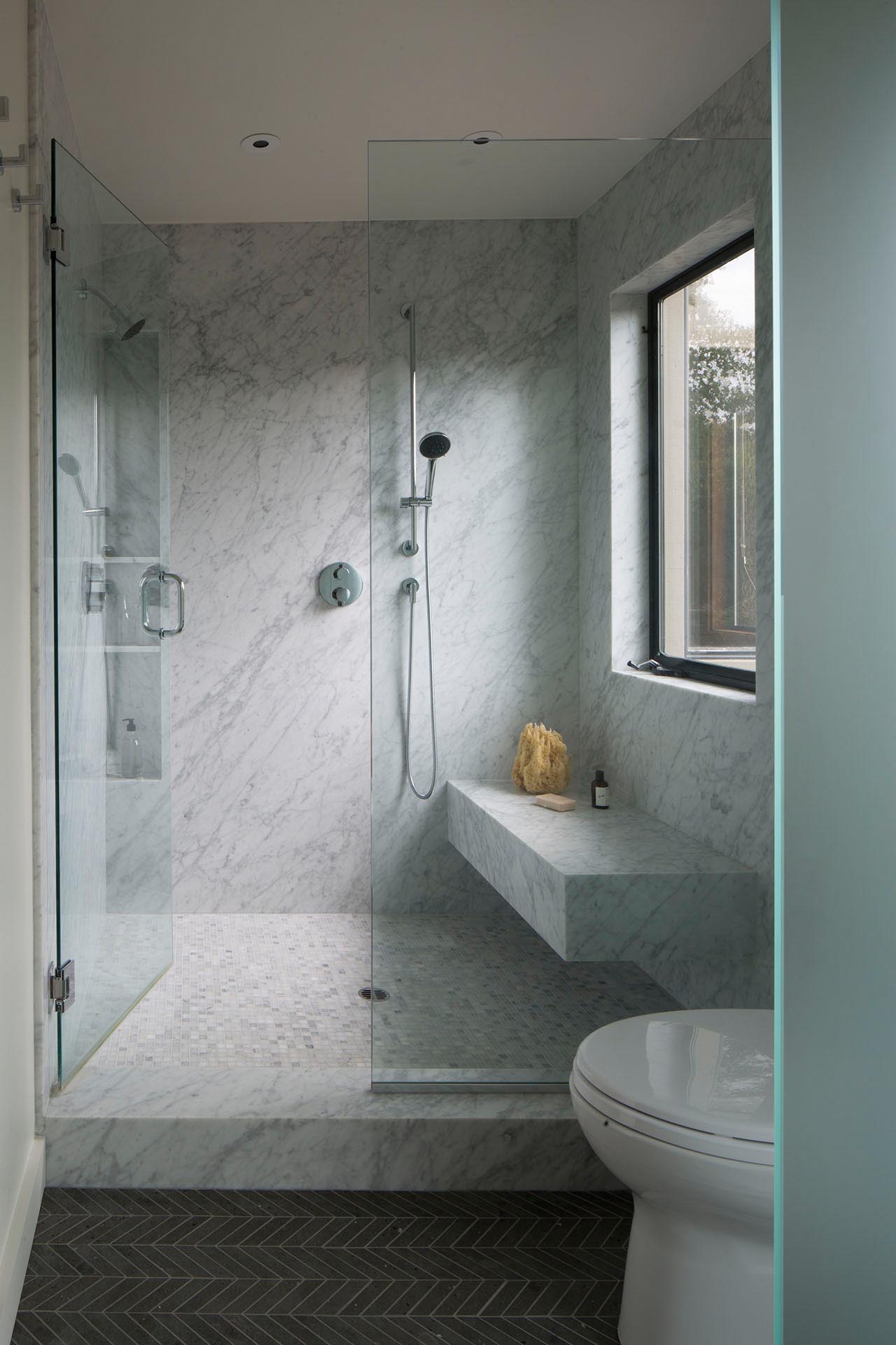 A modern bathroom with a walk-in shower that includes a bench and built-in shower niche.