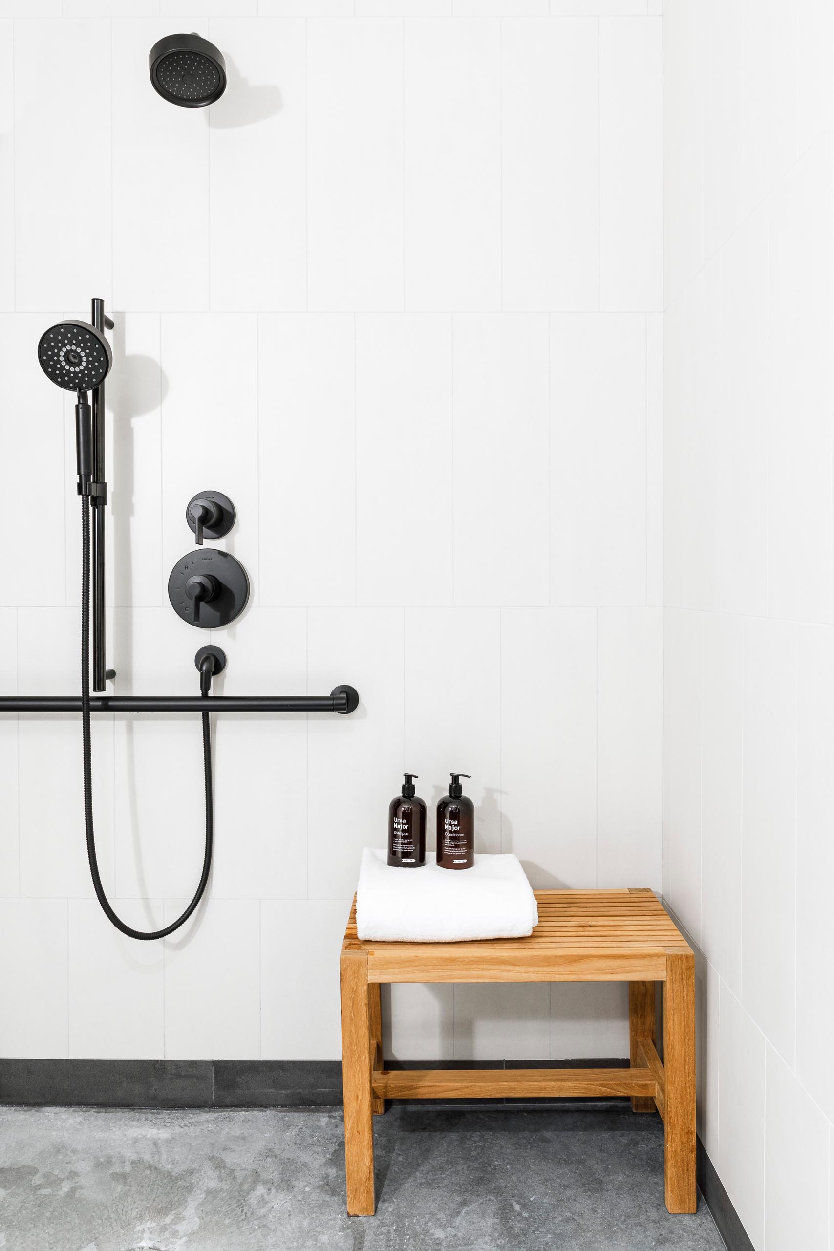 A modern bathroom with bright white tiled walls that contrast the black shower heads and hardware.