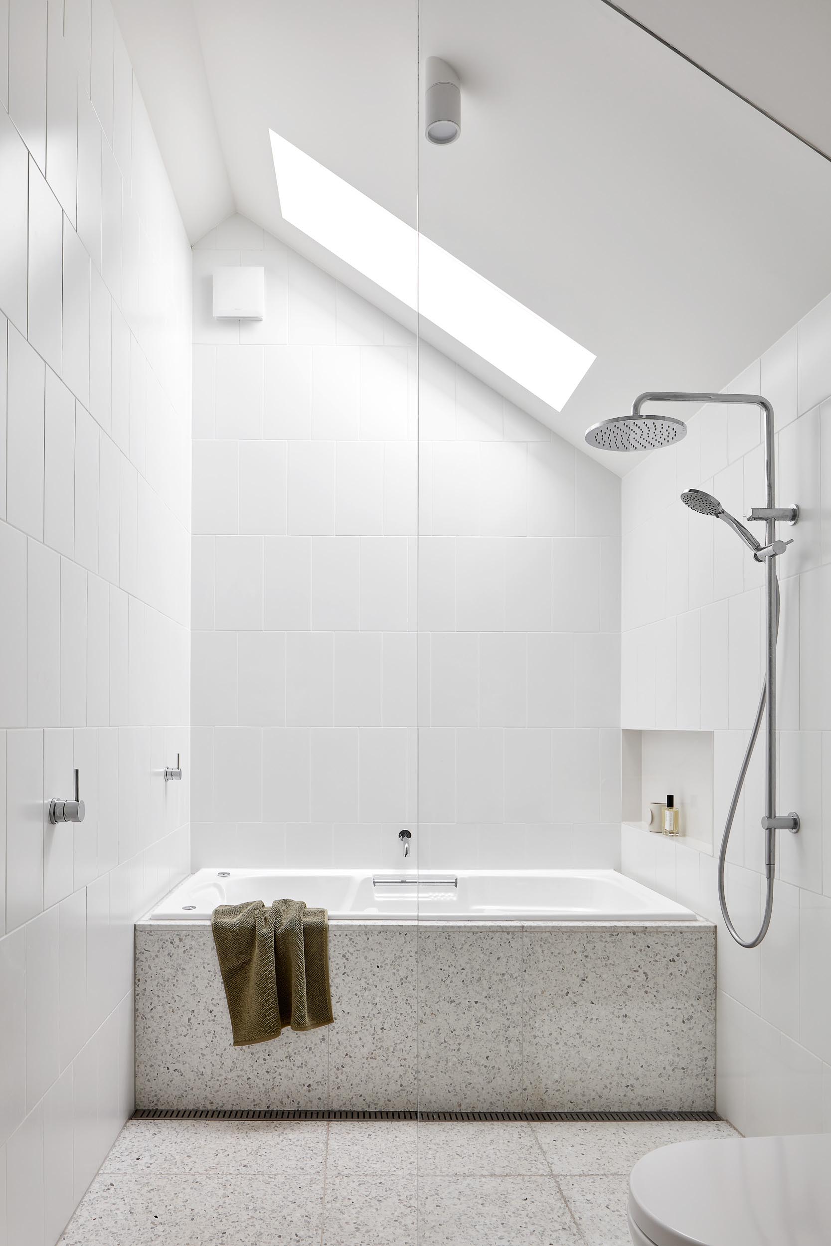 The terrazzo flooring in this bathroom travels through the shower and wraps onto the surround of the built-in bathtub.