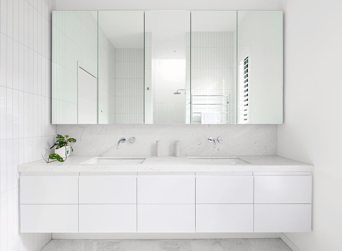 In this modern all white bathroom, honed Carrara Bianco marble was used for both the vanity countertop and the flooring.