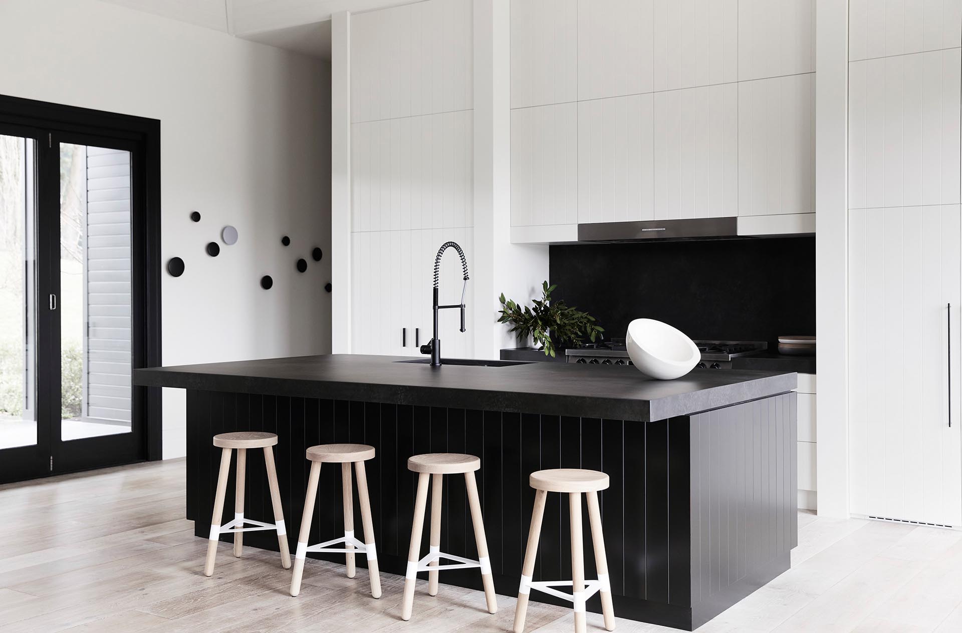 In this modern kitchen, there's minimalist white cabinets with integrated appliances, as well as a large black island that measures in at almost 10 feet (3m), and includes a black stone countertop that overhangs to provide room for seating.