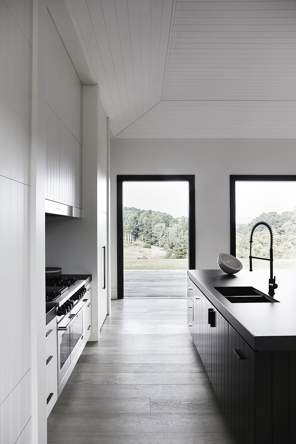 In this modern kitchen, there's minimalist white cabinets with integrated appliances, as well as a large black island that measures in at almost 10 feet (3m), and includes a black stone countertop that overhangs to provide room for seating.