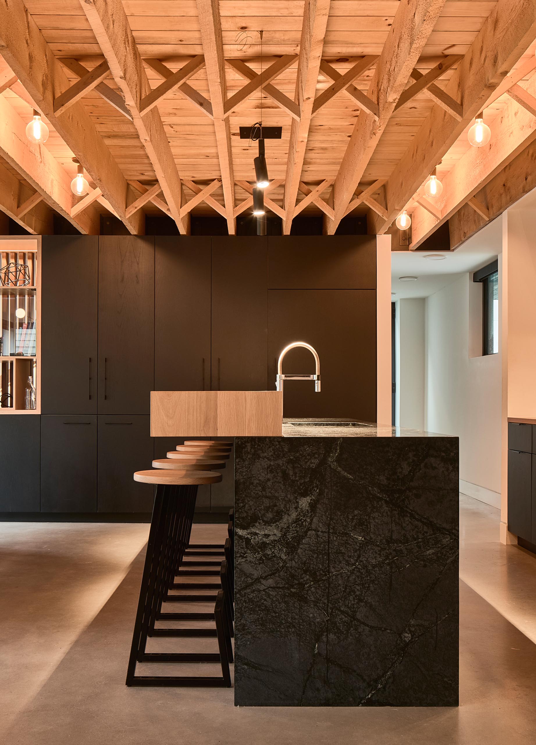 A modern kitchen with custom woodwork, black and wood countertops and black cabinets.