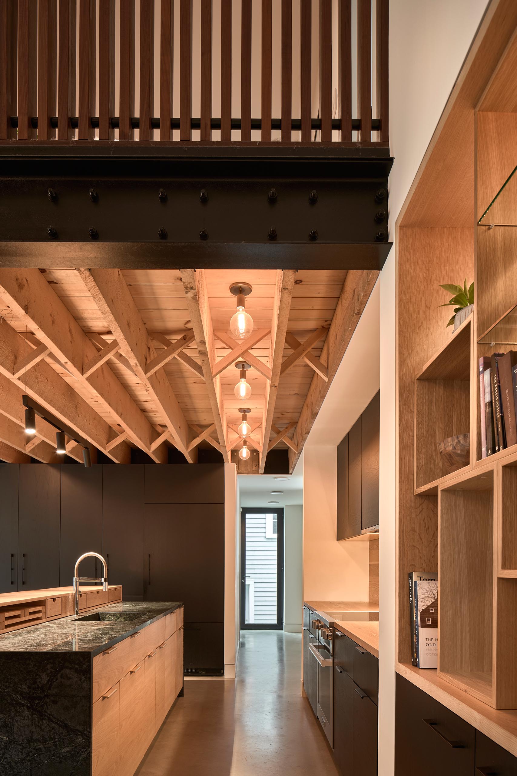 A modern kitchen with custom woodwork, black and wood countertops and black cabinets.