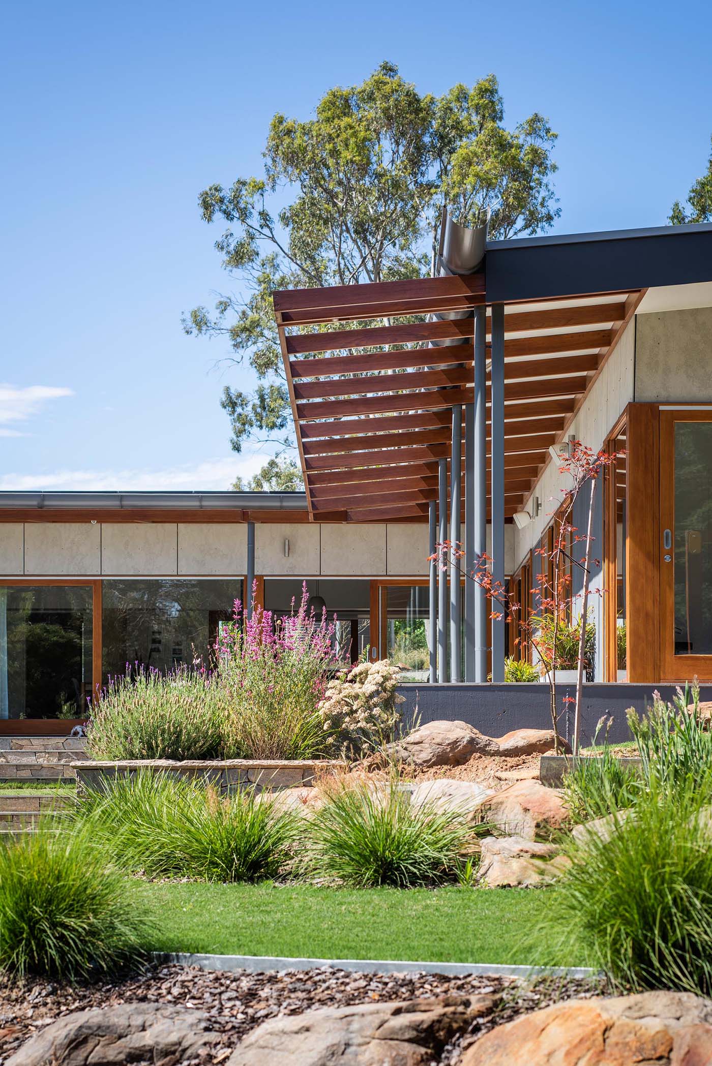 The different levels of the yard are complemented by large boulders and plants of varying sizes. These plants also line the rear patio that wraps around the home.