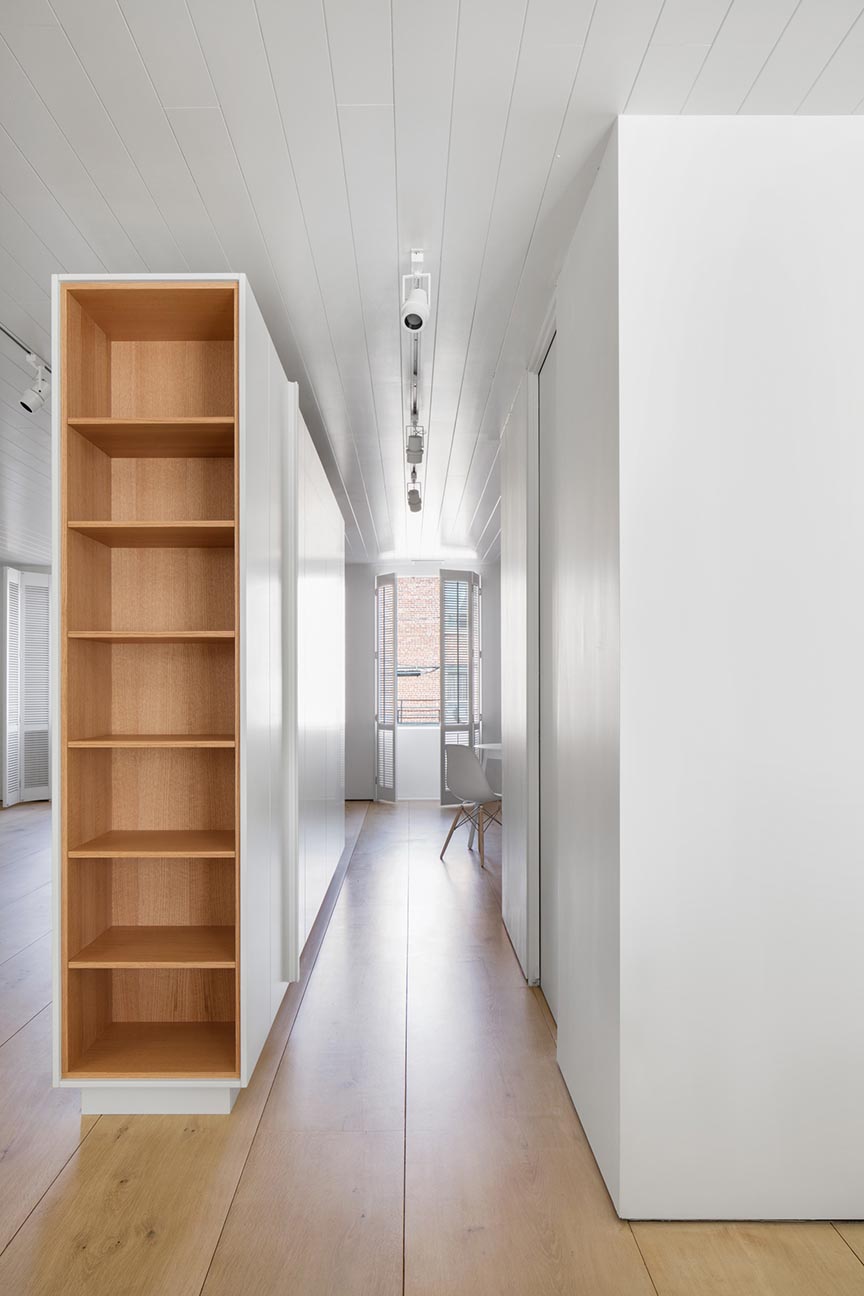 A modern office with wood lined shelves and wood floors.