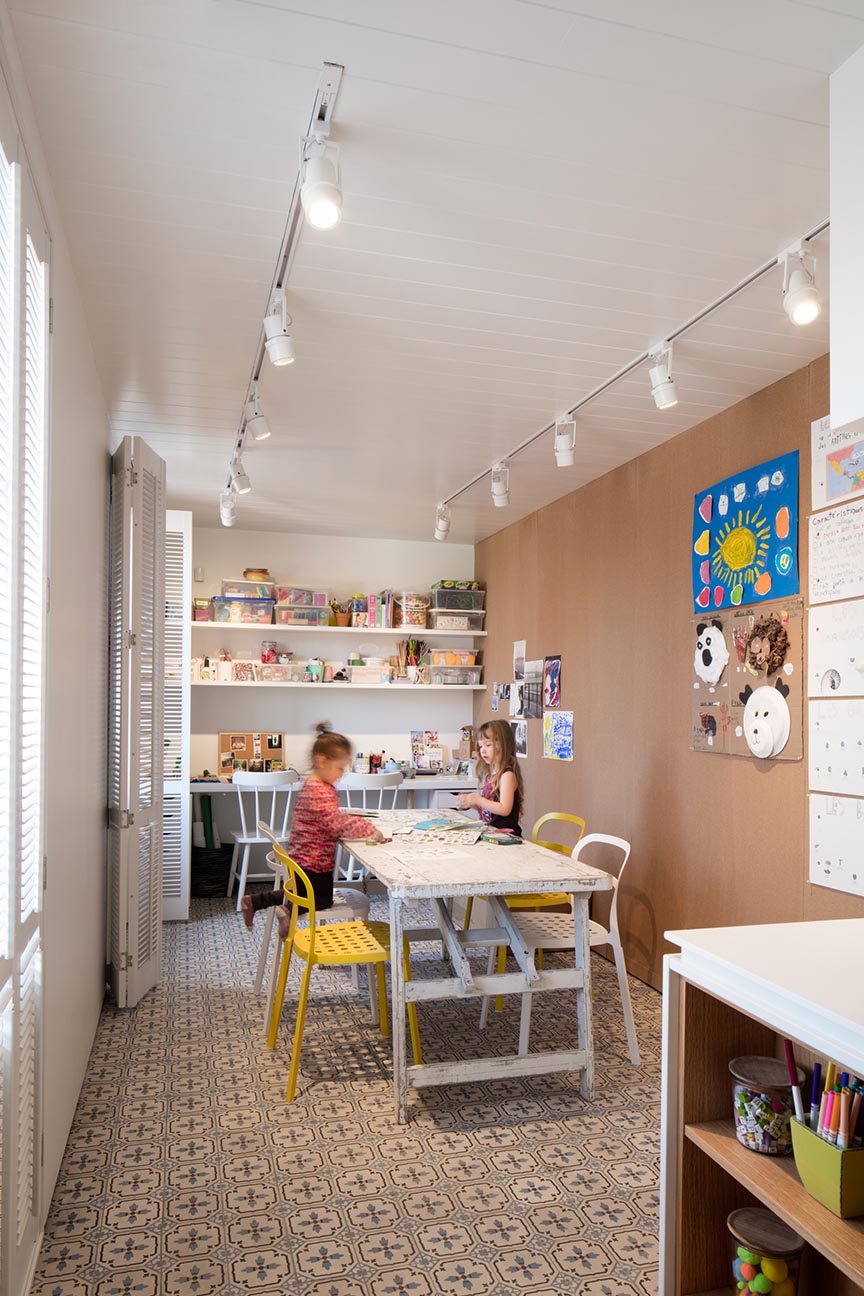 A modern playroom with shelving for storing craft items, and tables for creating.