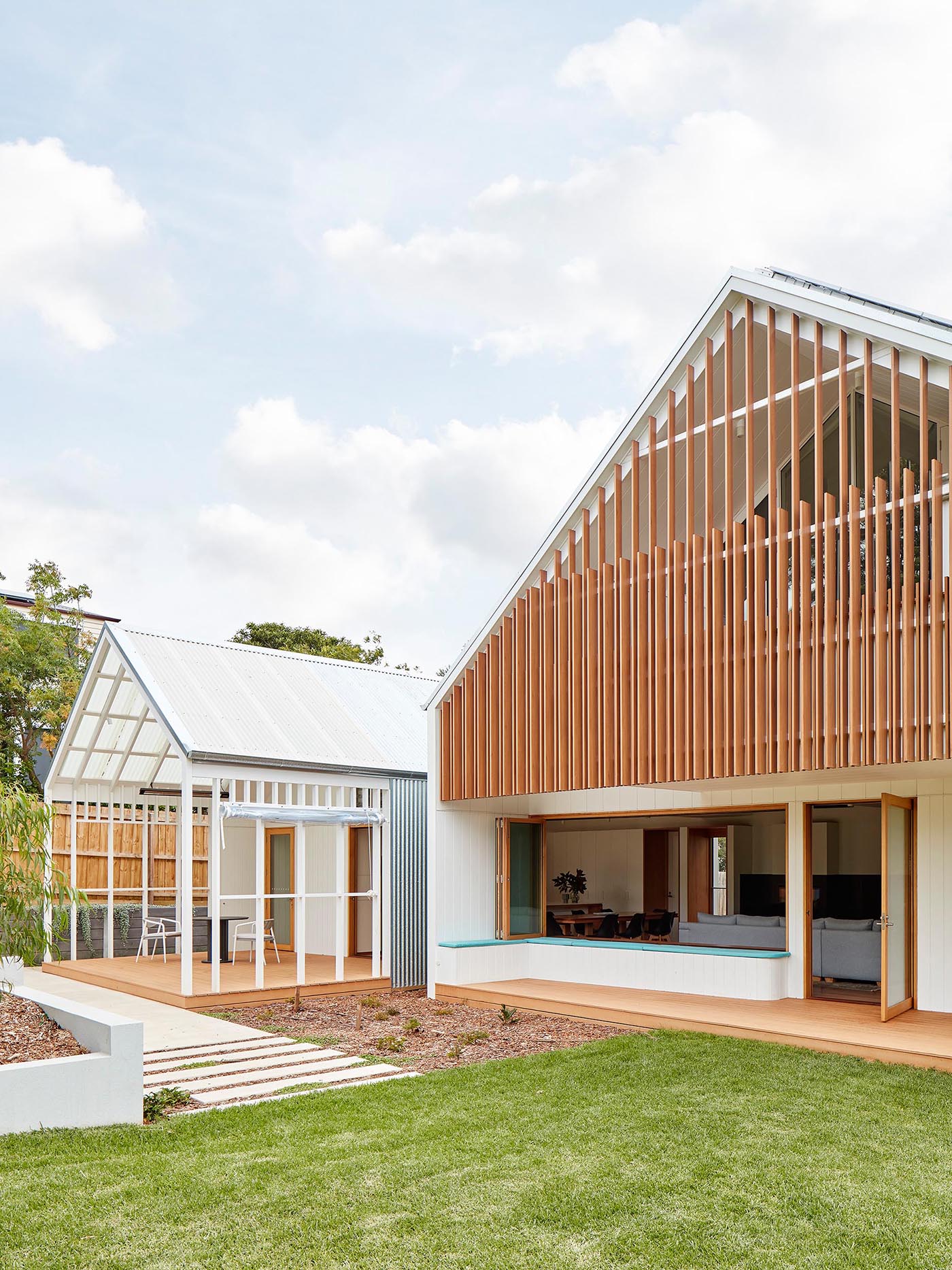 A modern house design with decks for outdoor dining and a built-in bench that wraps around the corner.