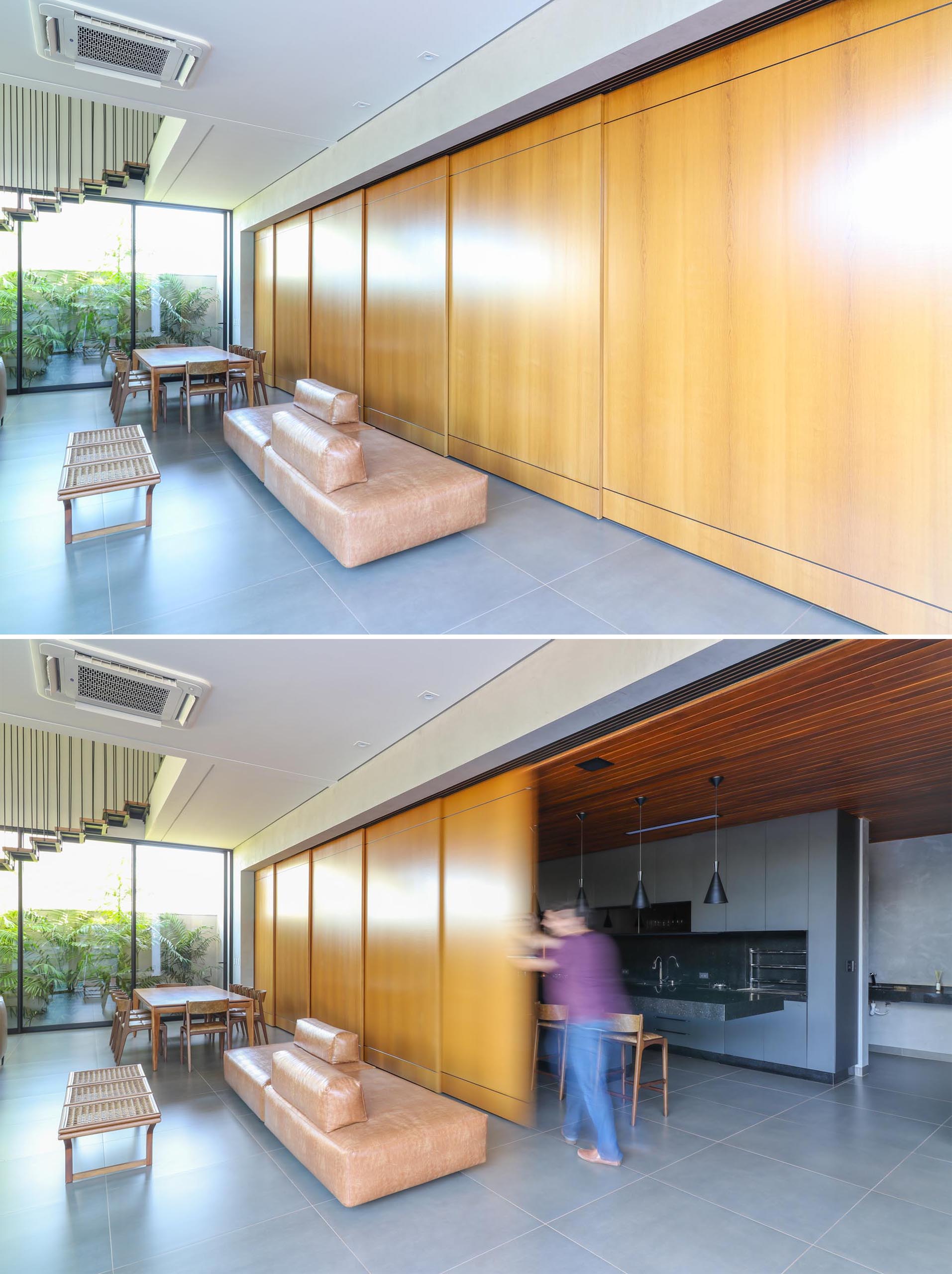 A modern home with a sliding wood wall that can hide the kitchen from the open plan dining area and living room.