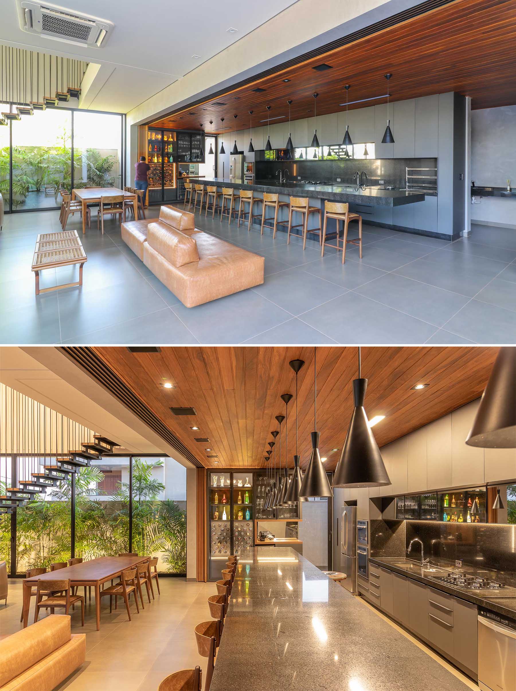 A modern home with a sliding wood wall that can hide the kitchen and expansive island from the open plan dining area and living room.