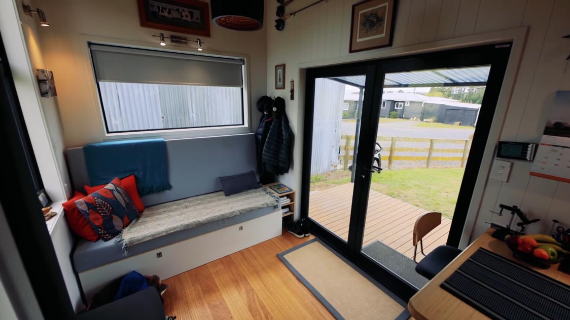 Stepping inside this modern tiny home, you're immediately met with the living room that includes a sofa that provides hidden storage as well as transforms into a bed for when guests visit.