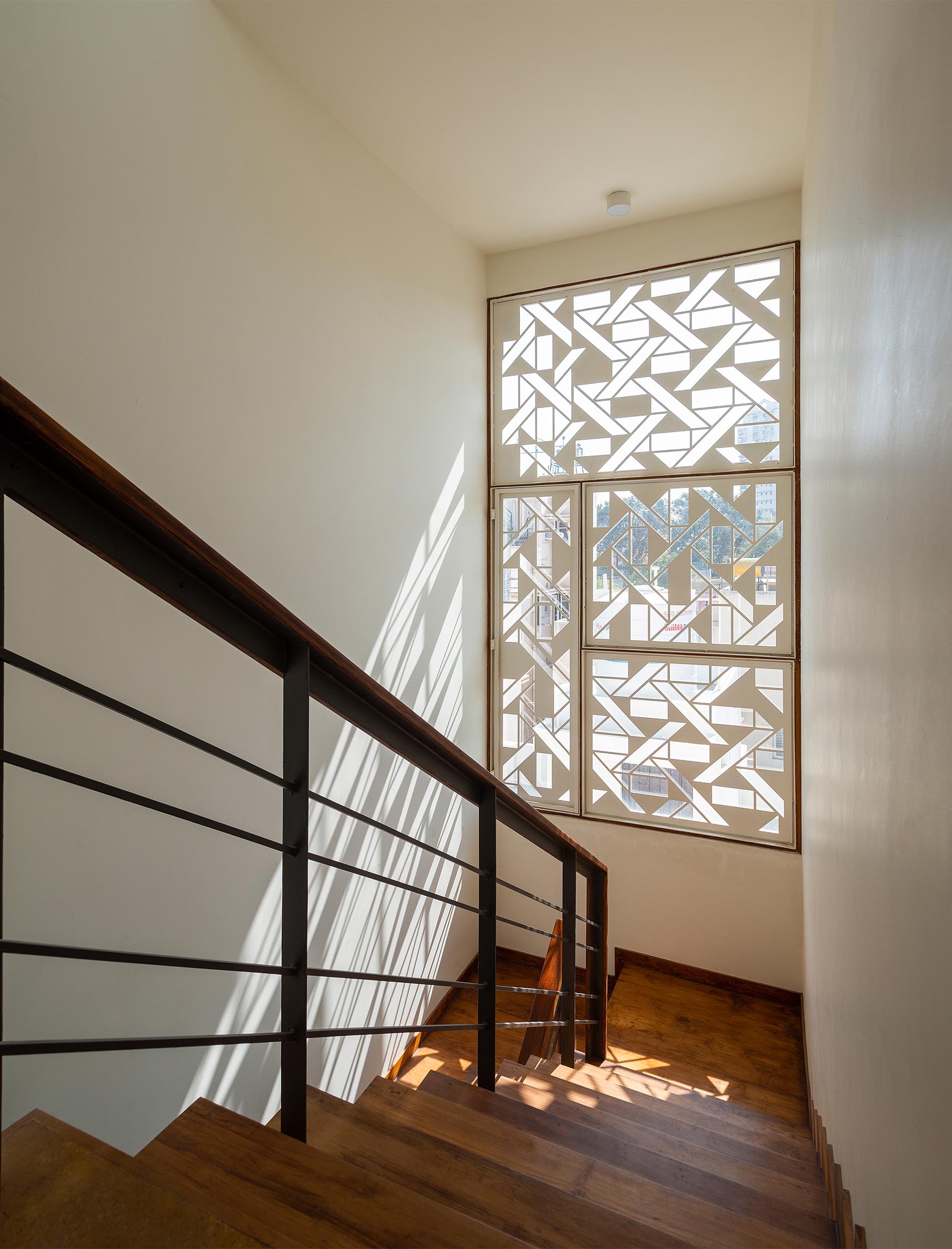 A white window screen with a geometric design casts interesting shadows on the walls and floor.