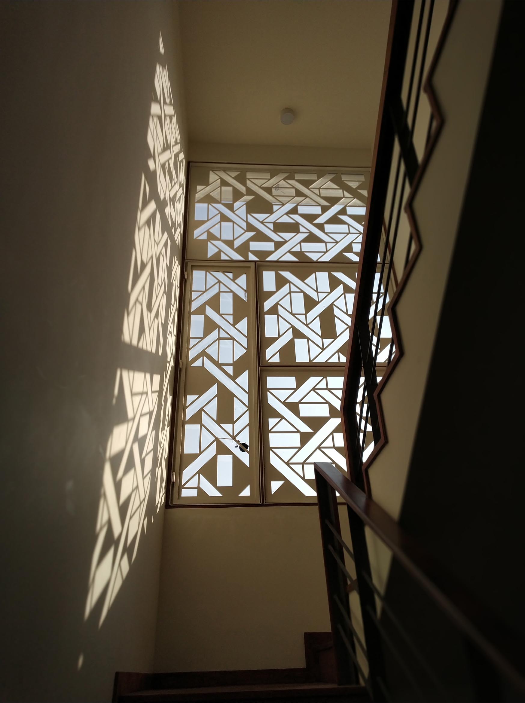 A white window screen with a geometric design casts interesting shadows on the walls and floor.