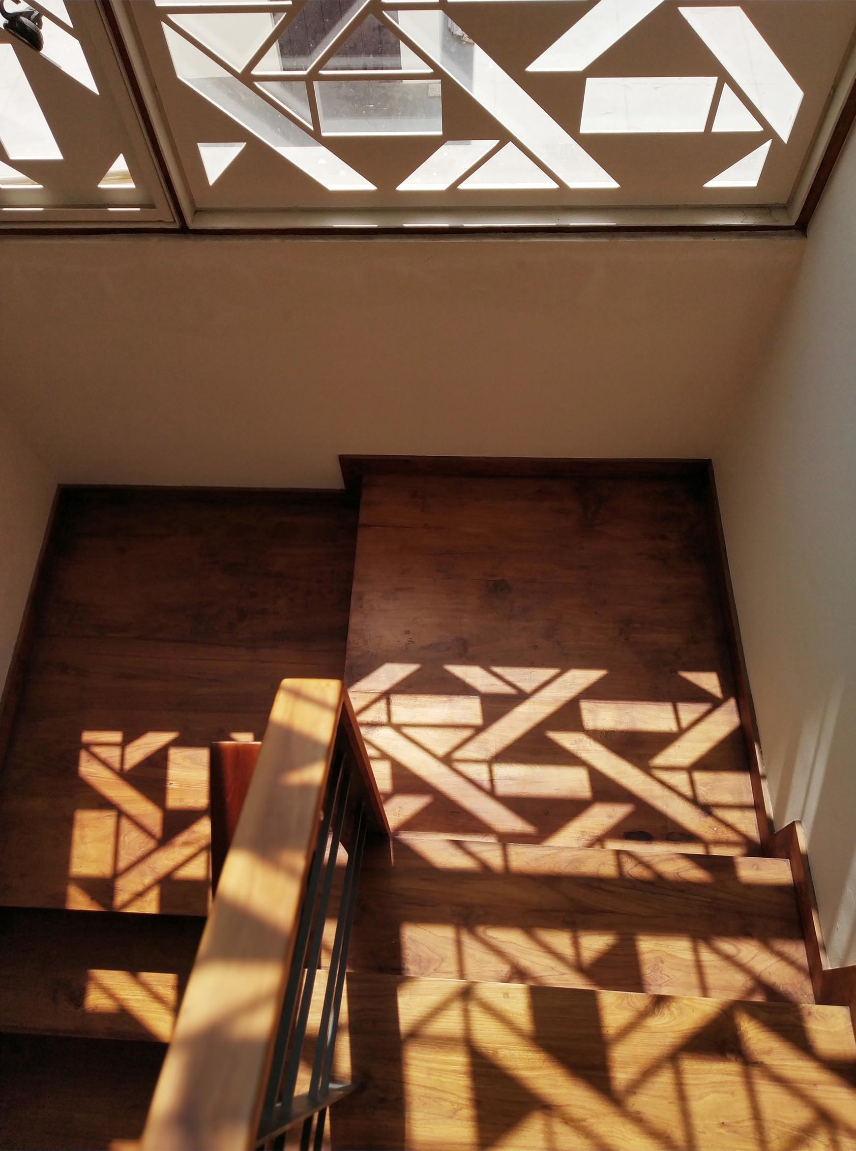 A white window screen with a geometric design casts interesting shadows on the walls and floor.