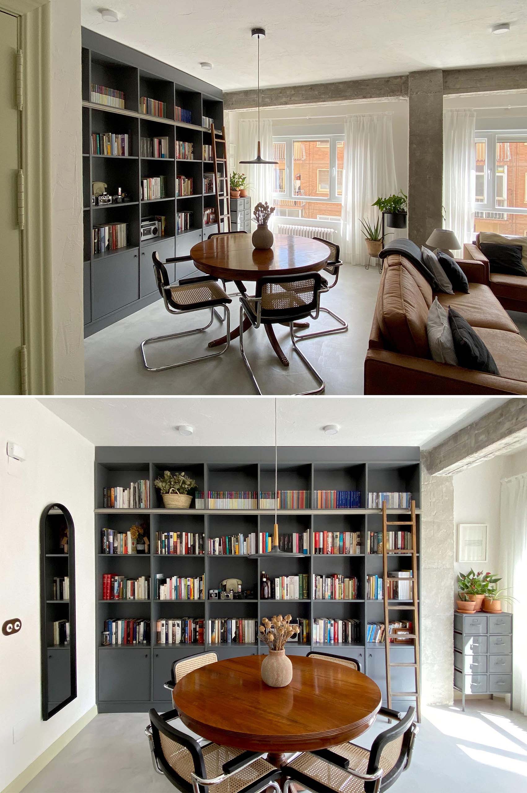 A full wall of custom cabinetry and open shelving, with a ladder, acts as a library, while a round dining table sits beneath a single minimalist pendant light.