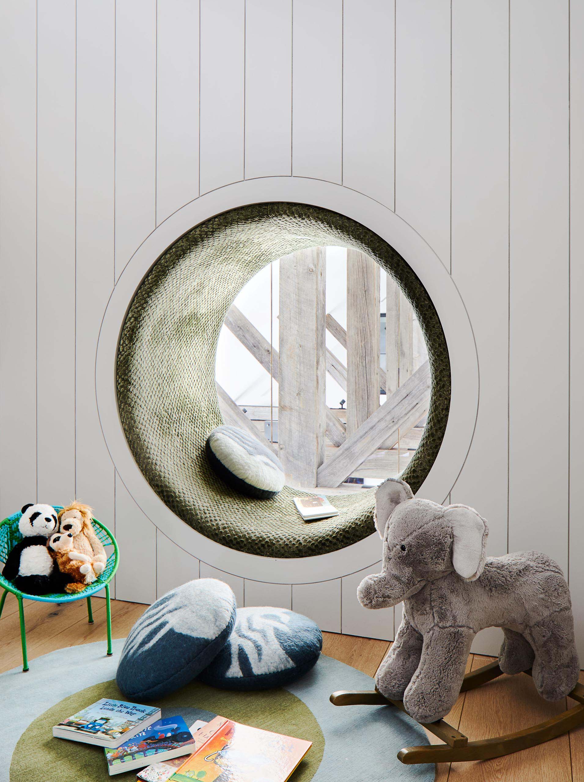 In this modern kids room, there's a cozy round window seat with an upholstered cushion that lines the space.