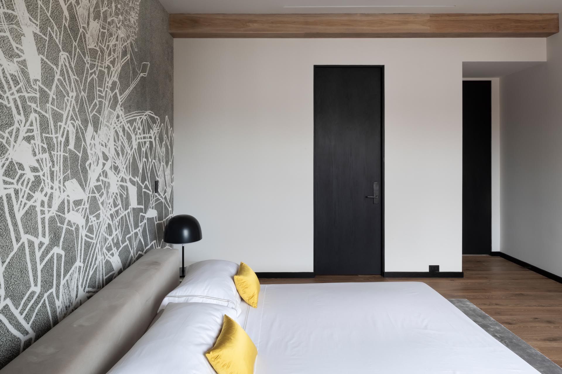 A modern bedroom with a gray and white geometric wallpaper.