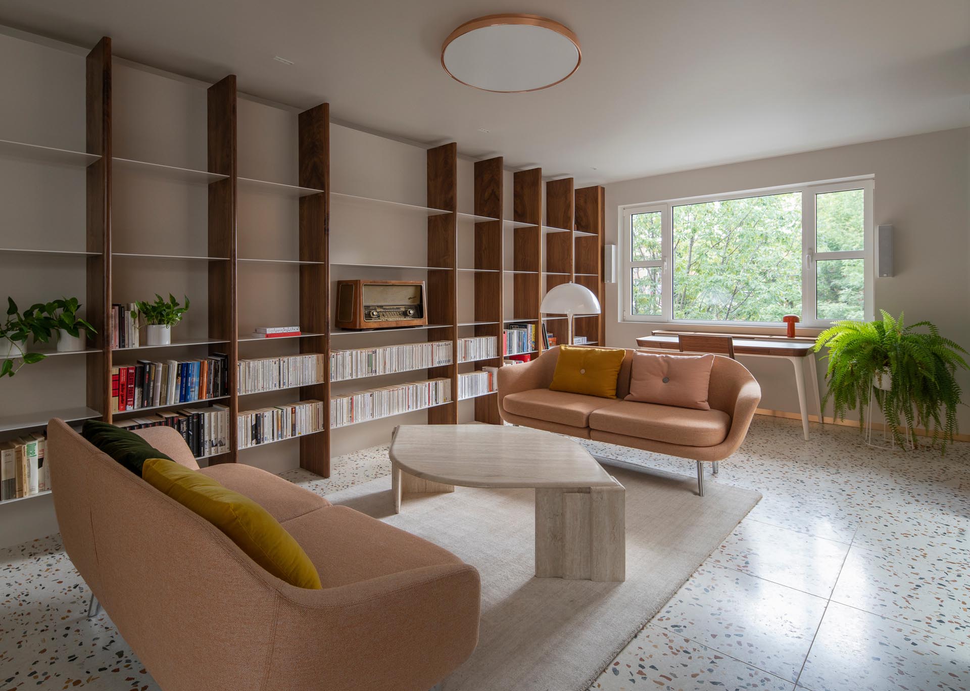 A modern living room with terrazzo tile floors, and a custom wood and metal bookshelf.