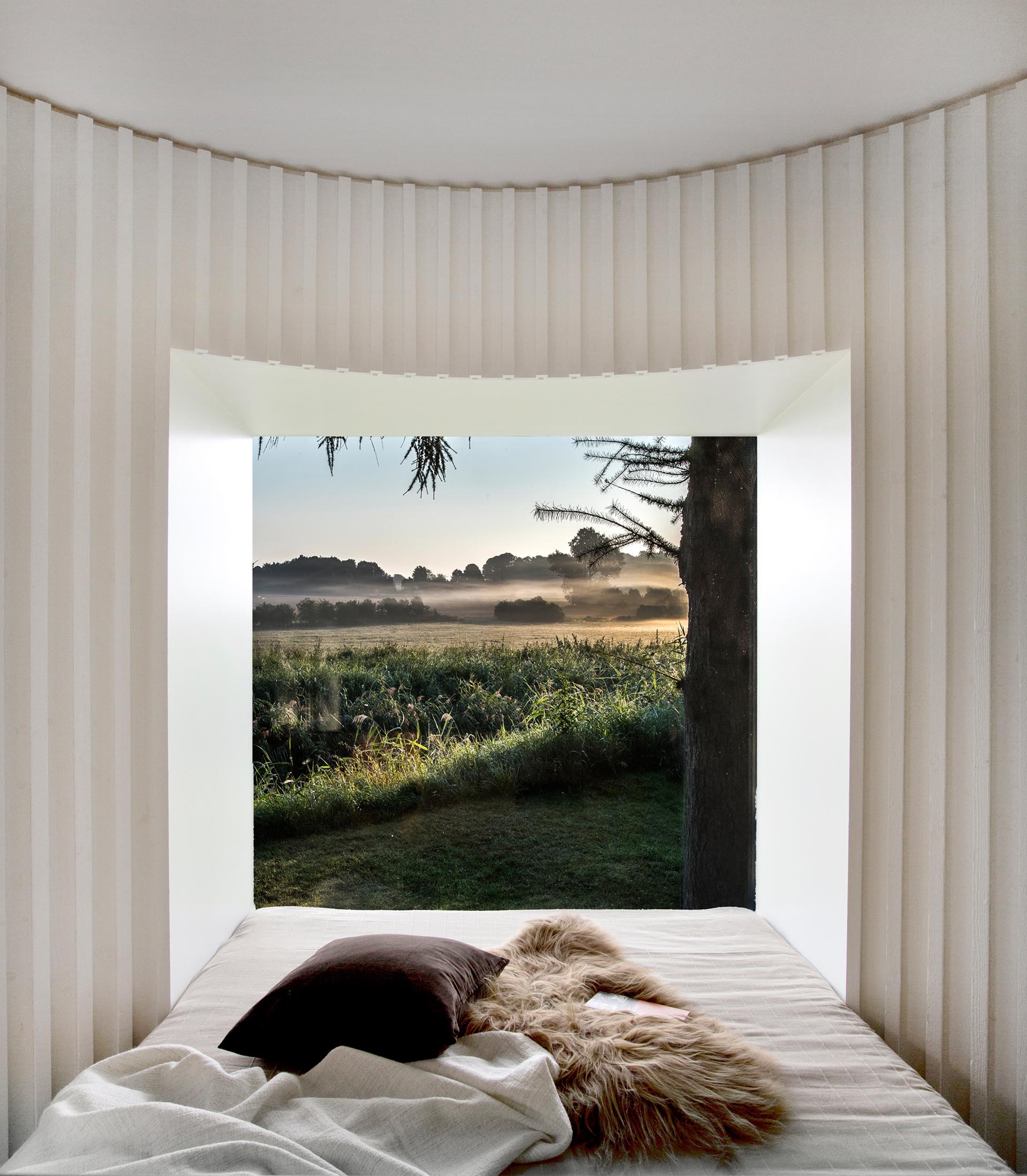 In this curved bedroom, a desk is positioned behind the headboard, while at the end of the is a picture window for unobstructed views.