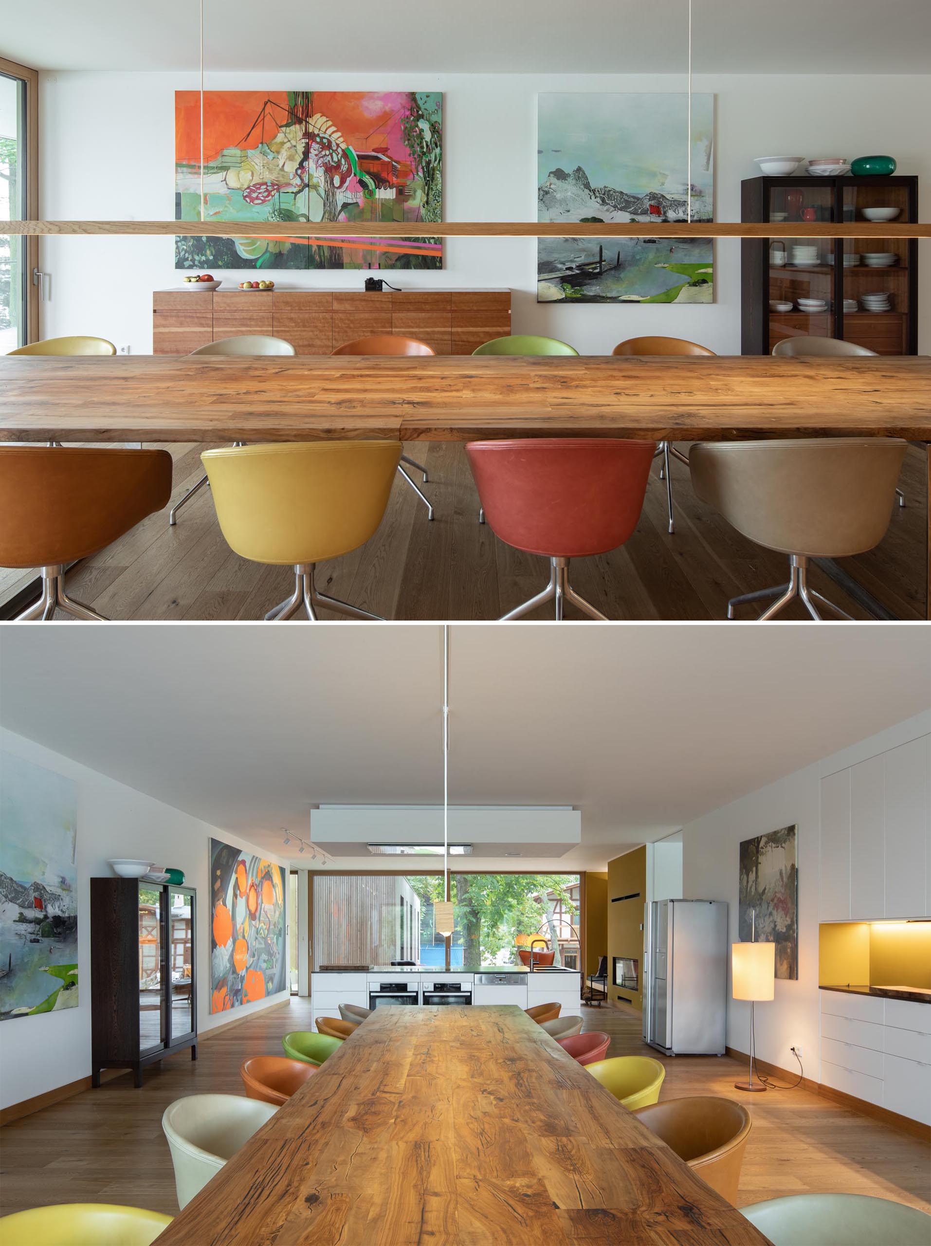 A modern dining room with an oversized wood table, matching minimalist pendant light, and colorful artwork.