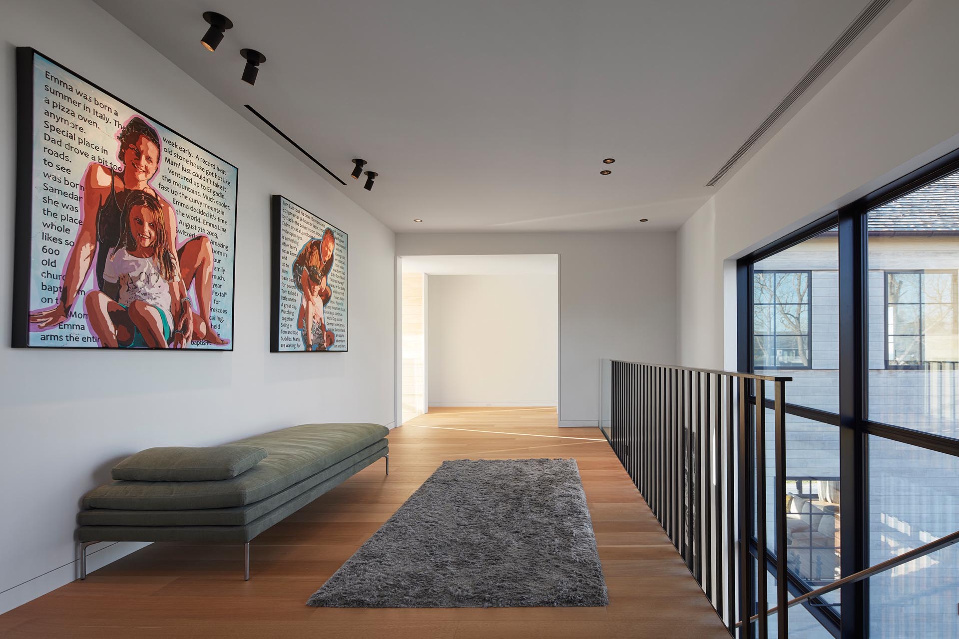 At the top of the stairs in this modern house, there's an open hallway with a seating area that connects to the bedrooms and bathrooms.