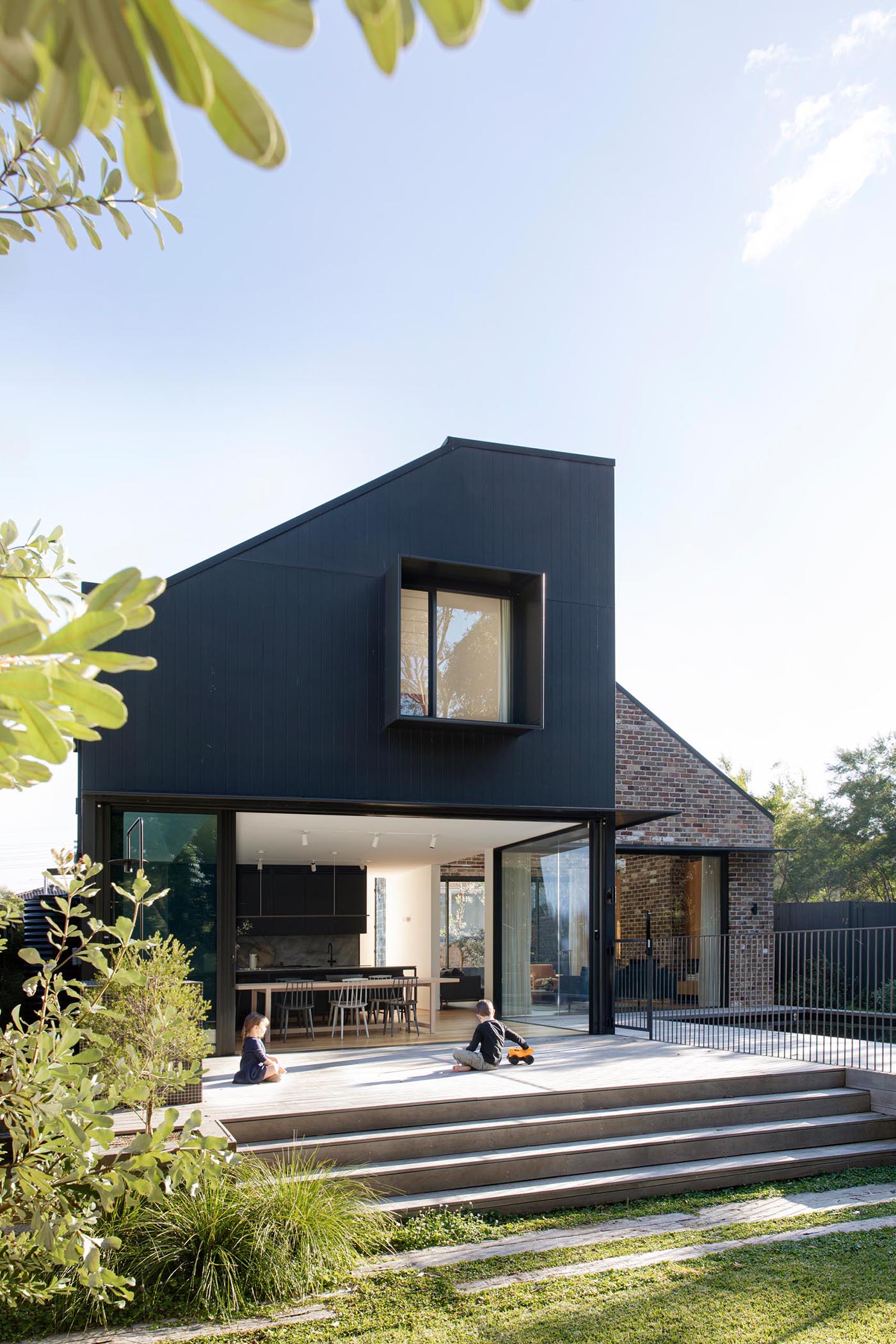 A sliding glass wall opens the interior spaces to a greyed Blackbutt deck with an outdoor kitchen that steps down to the yard, as well as a swimming pool.