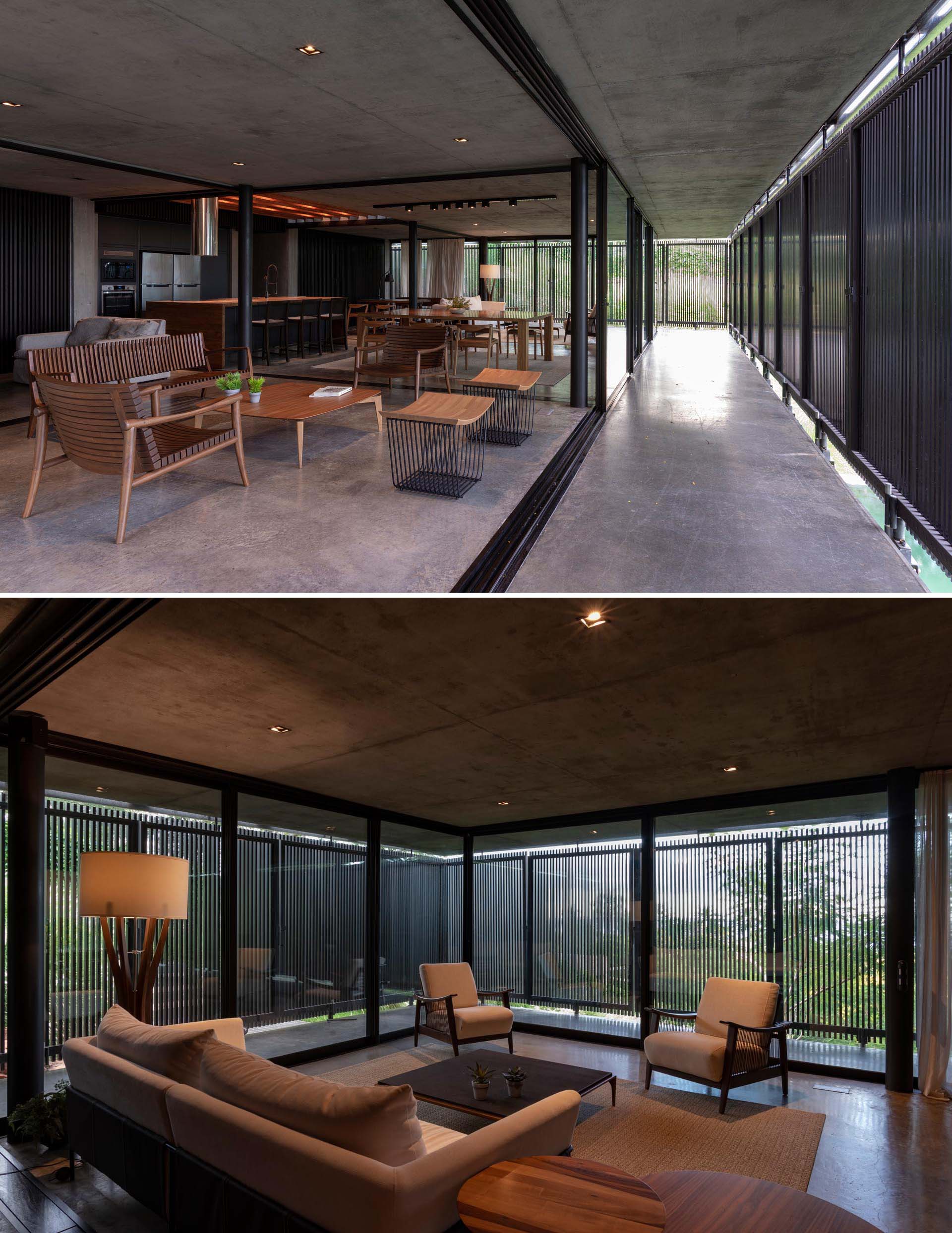 A modern house with an open floor plan, black wood slat screens, glass walls, and concrete floors.